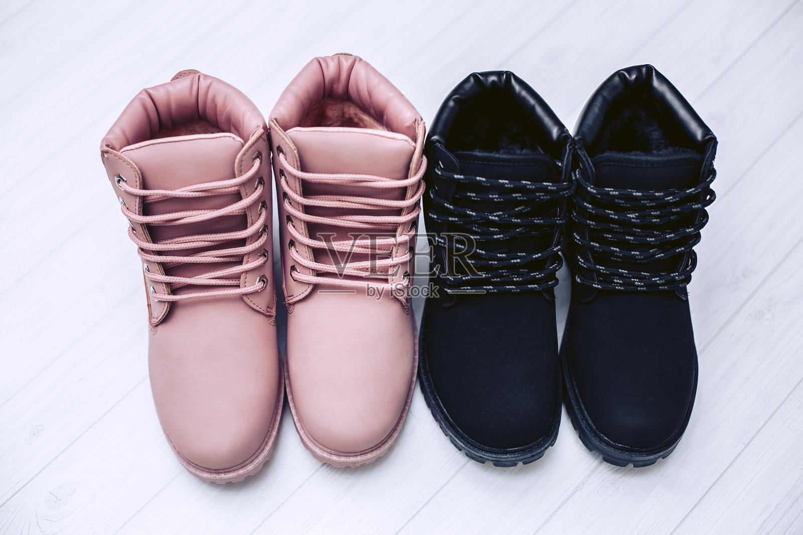 女士的冬季靴子的粉红色和黑色的颜色上的白色木制背景。照片摄影图片