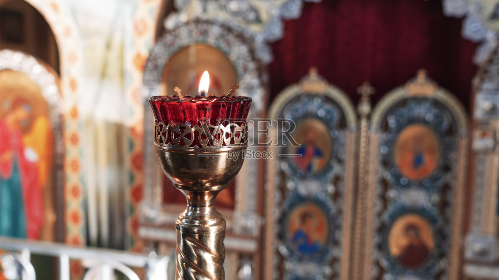 东正教教堂灯与点燃的蜡烛和红色玻璃在图标的背景。照片摄影图片