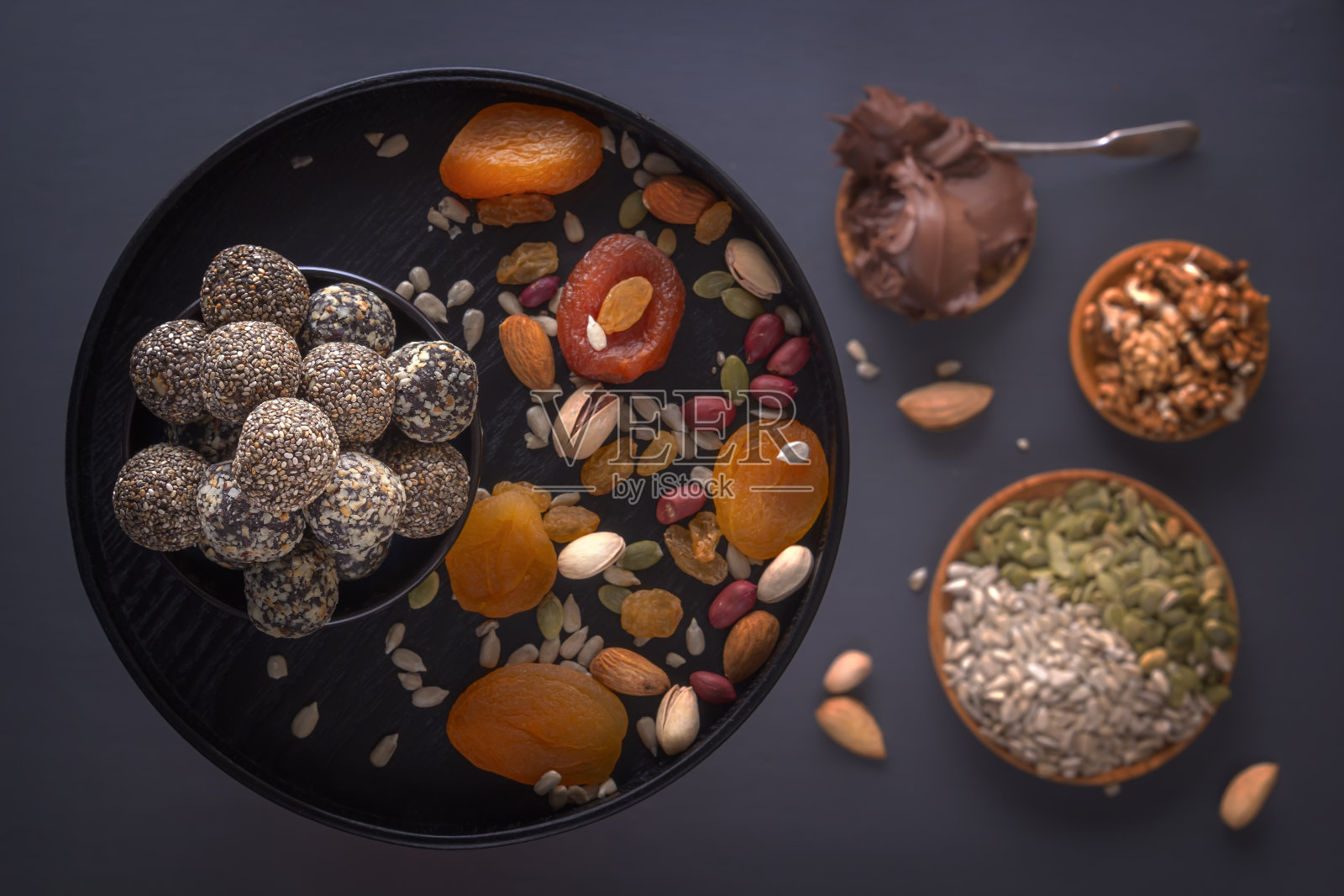 黑色的桌子上放着天然健康的能量食物，巧克力酱，干果和坚果。照片摄影图片