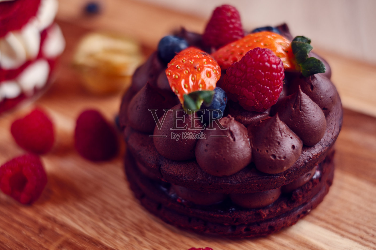 木桌上有小块巧克力蛋糕，上面有覆盆子和草莓照片摄影图片