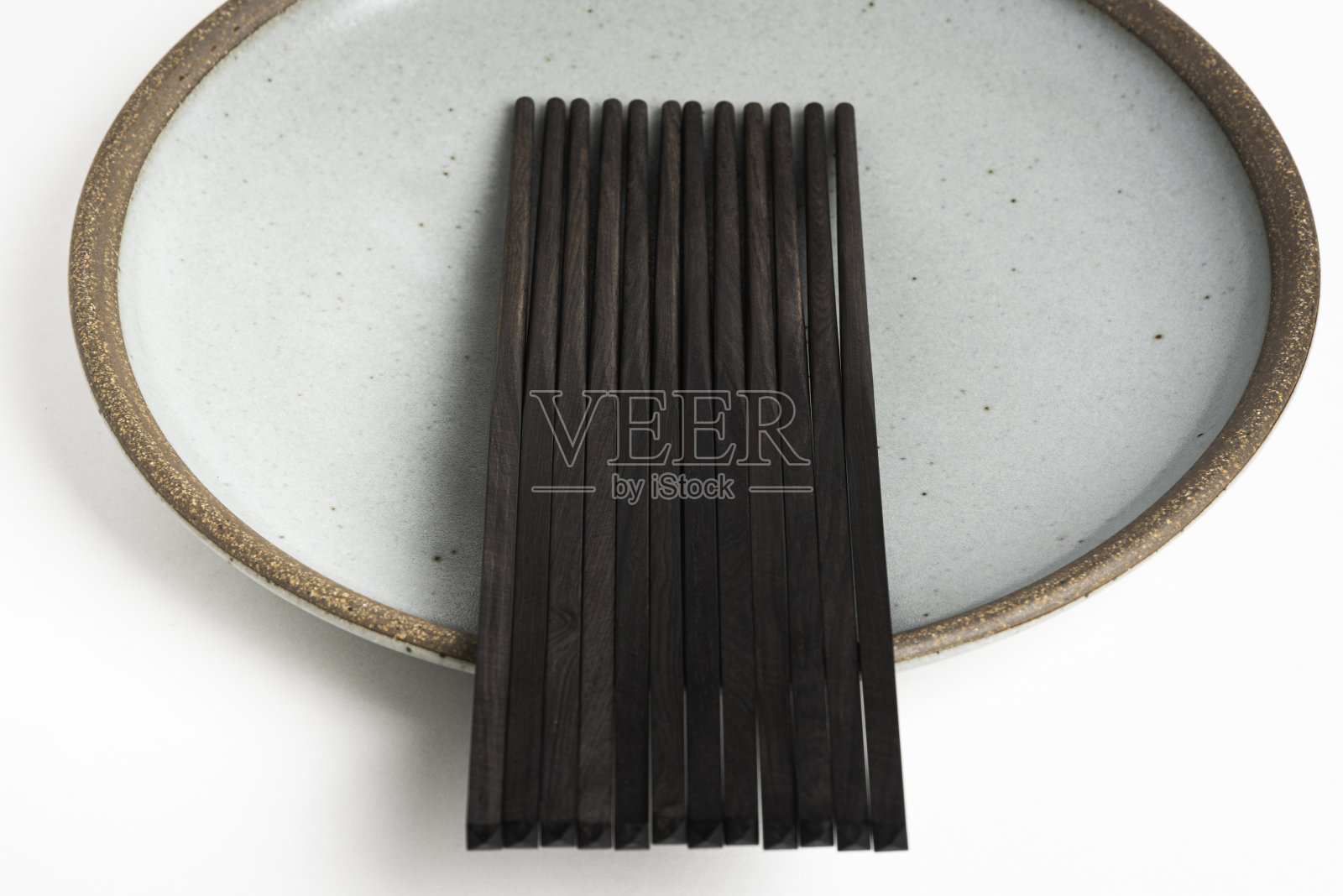 六双筷子放在炻器盘子上照片摄影图片