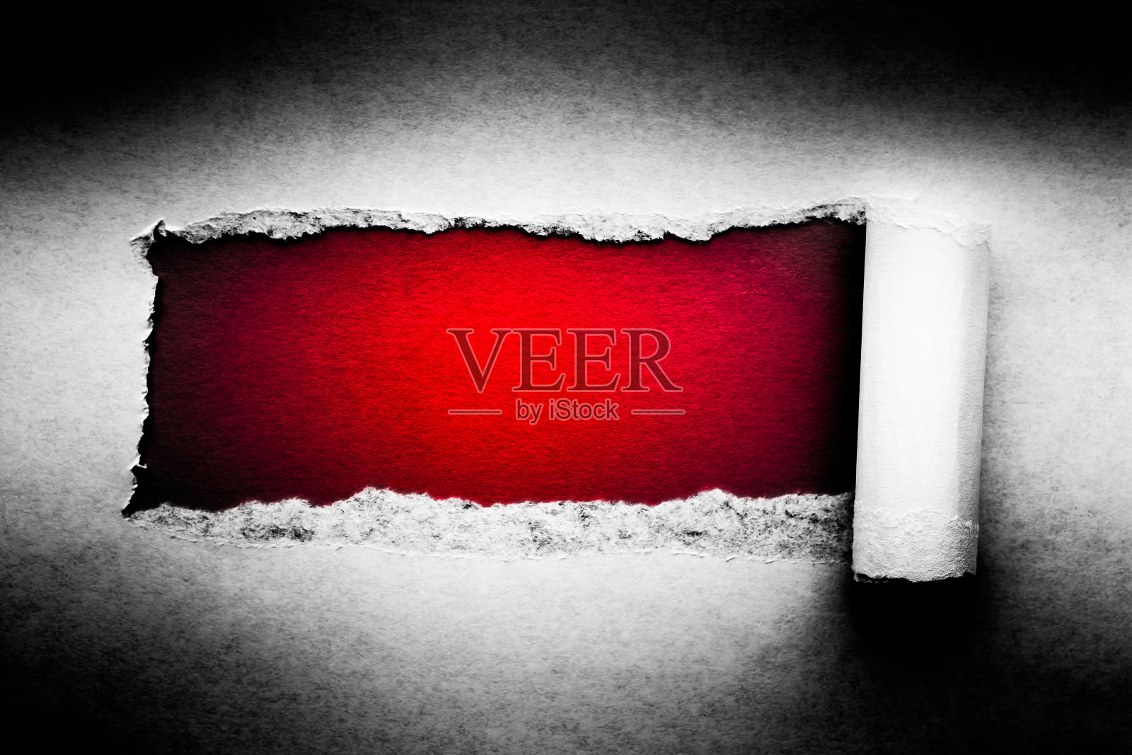 一个洞在旧纸与撕破边缘特写与红色充满活力的背景里面。照片摄影图片