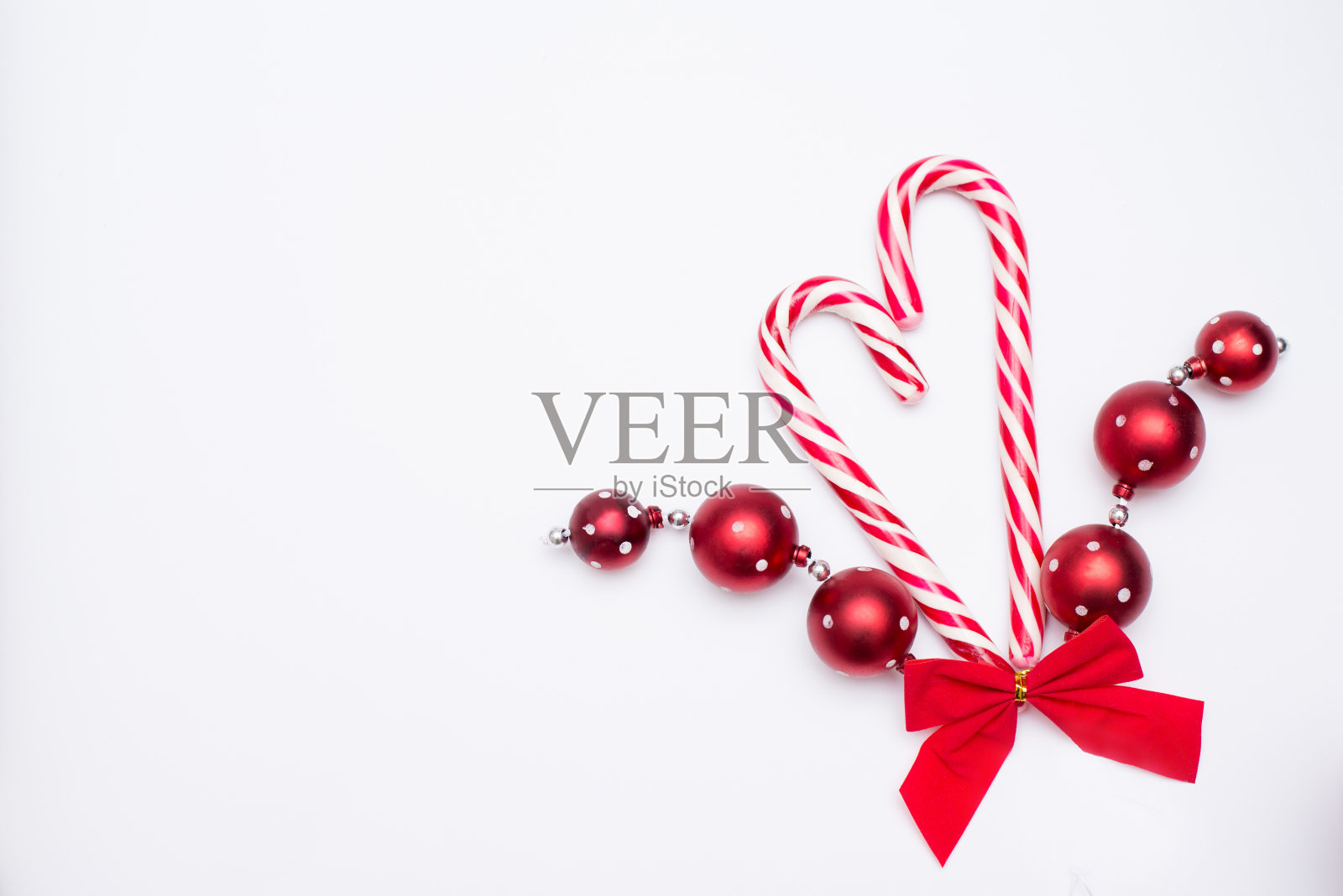 两根心形糖果手杖与红色蝴蝶结和新年装饰孤立在白色背景。照片摄影图片