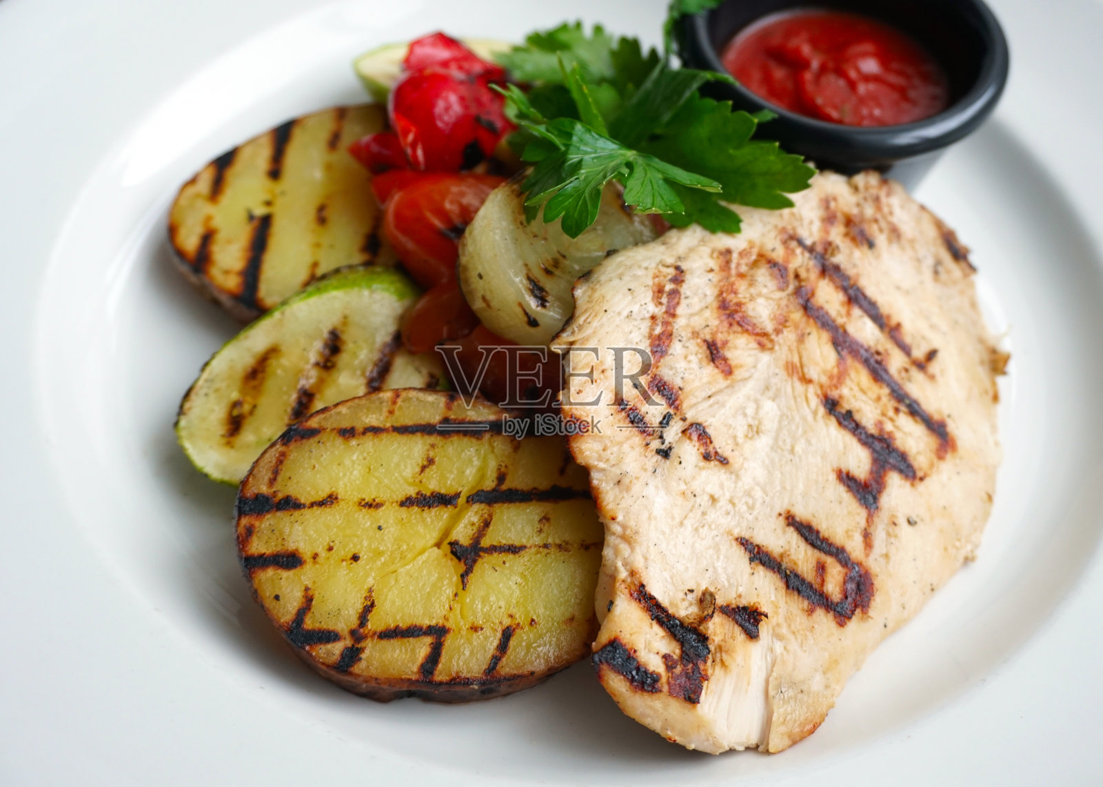 白盘子上的烤鸡和蔬菜照片摄影图片