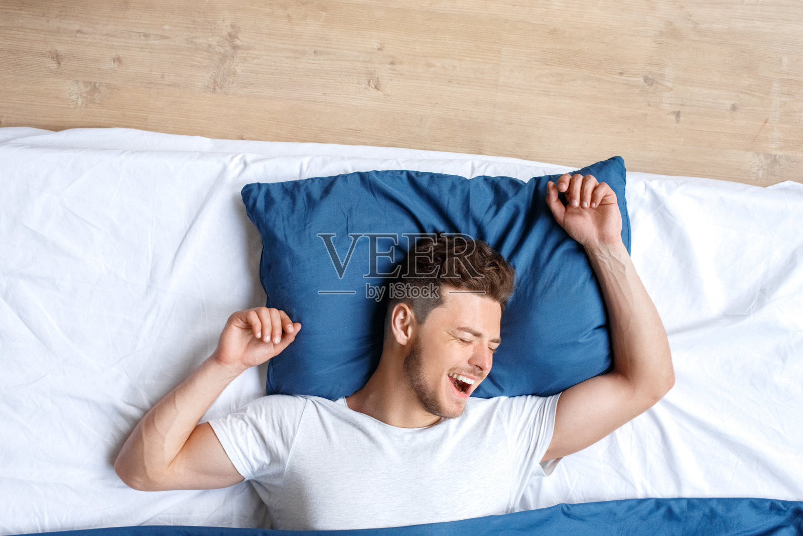 睡觉前。男人躺在床上俯视图醒来打哈欠伸懒腰快乐照片摄影图片