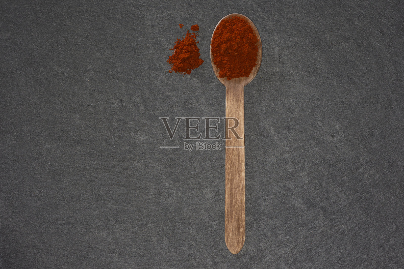 木勺和玫瑰红辣椒在黑色石板盘子照片摄影图片