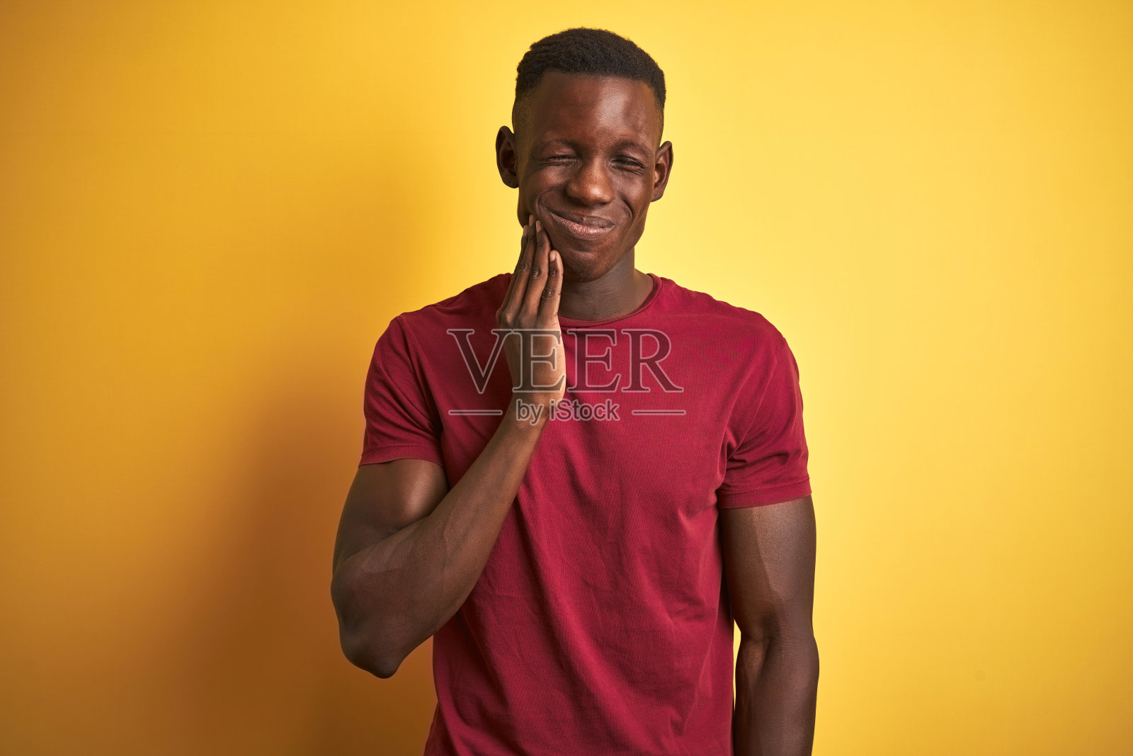 年轻的非洲裔美国人身穿红色t恤站在孤立的黄色背景与手触摸嘴痛苦的表情，因为牙痛或牙齿疾病的牙齿。牙医的概念。照片摄影图片