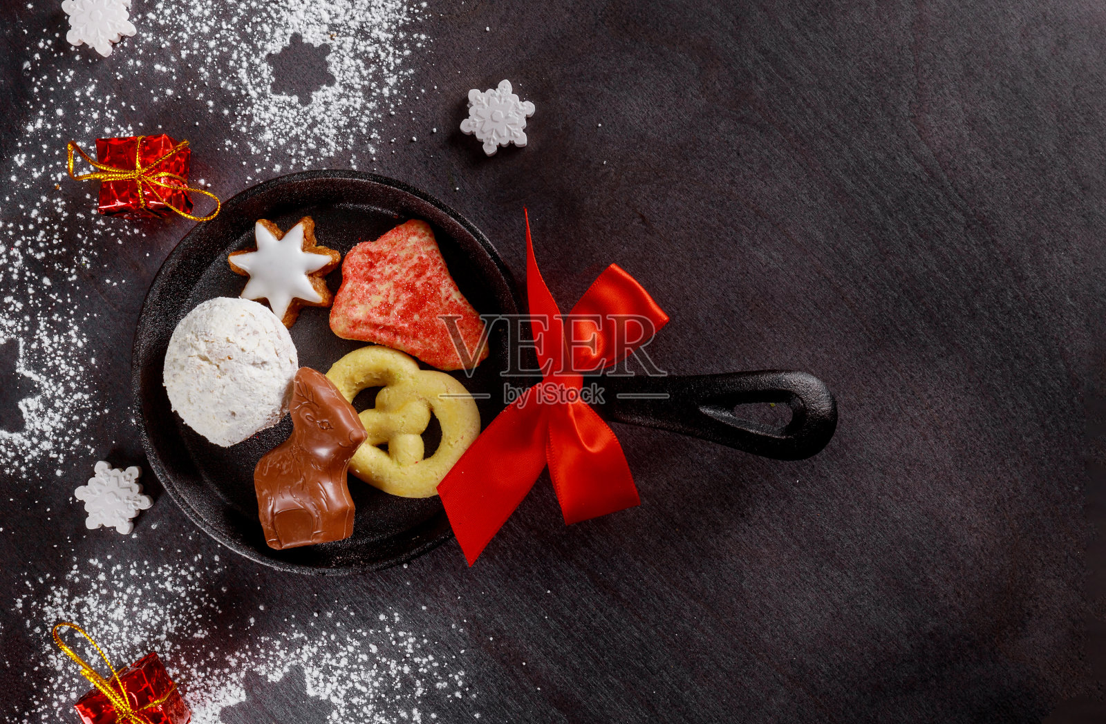 黑色的桌子上放着圣诞饼干和巧克力。照片摄影图片