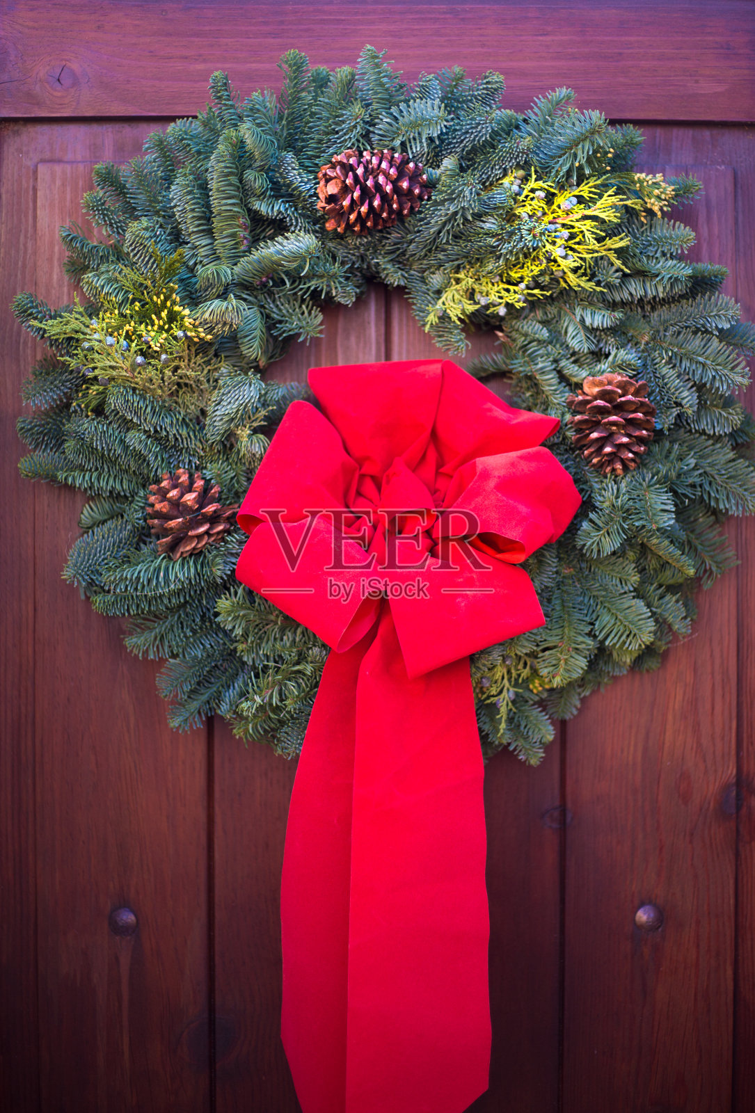 绿色圣诞花环，松果，红色蝴蝶结，木门照片摄影图片