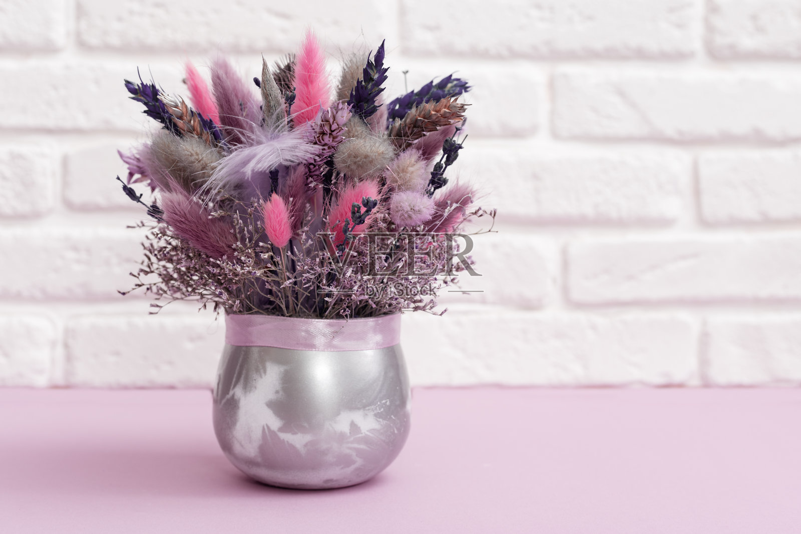 潮流美丽的粉紫色干花花束，花，草。白色砖墙上手工花卉装饰。照片摄影图片