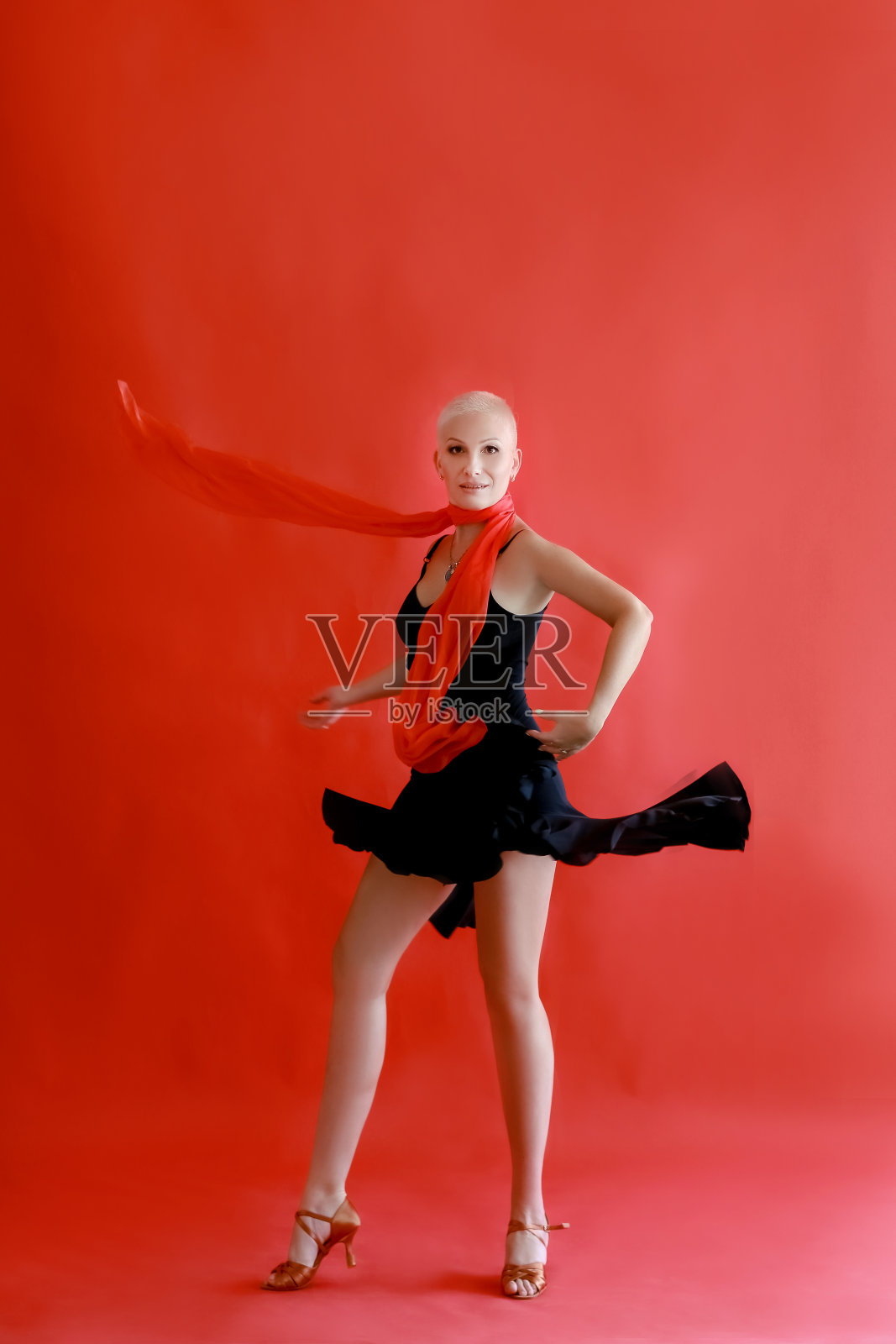 40岁45岁的女人穿着黑色裙子在红色背景上跳探戈照片摄影图片