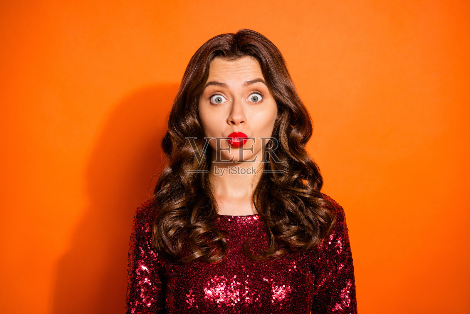 她的特写肖像，她漂亮的，迷人的，迷人的，可爱的，可爱的，漂亮的波浪形的头发的女孩送飞吻孤立在明亮的，生动的，闪亮的，充满活力的橙色背景照片摄影图片