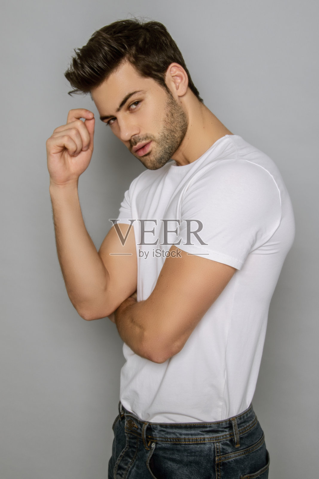 肌肉强壮美丽的剥离男性模特在牛仔蓝色牛仔裤和白色t恤灰色孤立的字体背景照片摄影图片