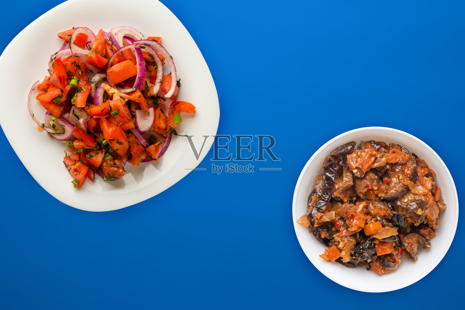 素食。番茄，洋葱，莳萝，白色盘子，背景颜色。健康的食物照片摄影图片