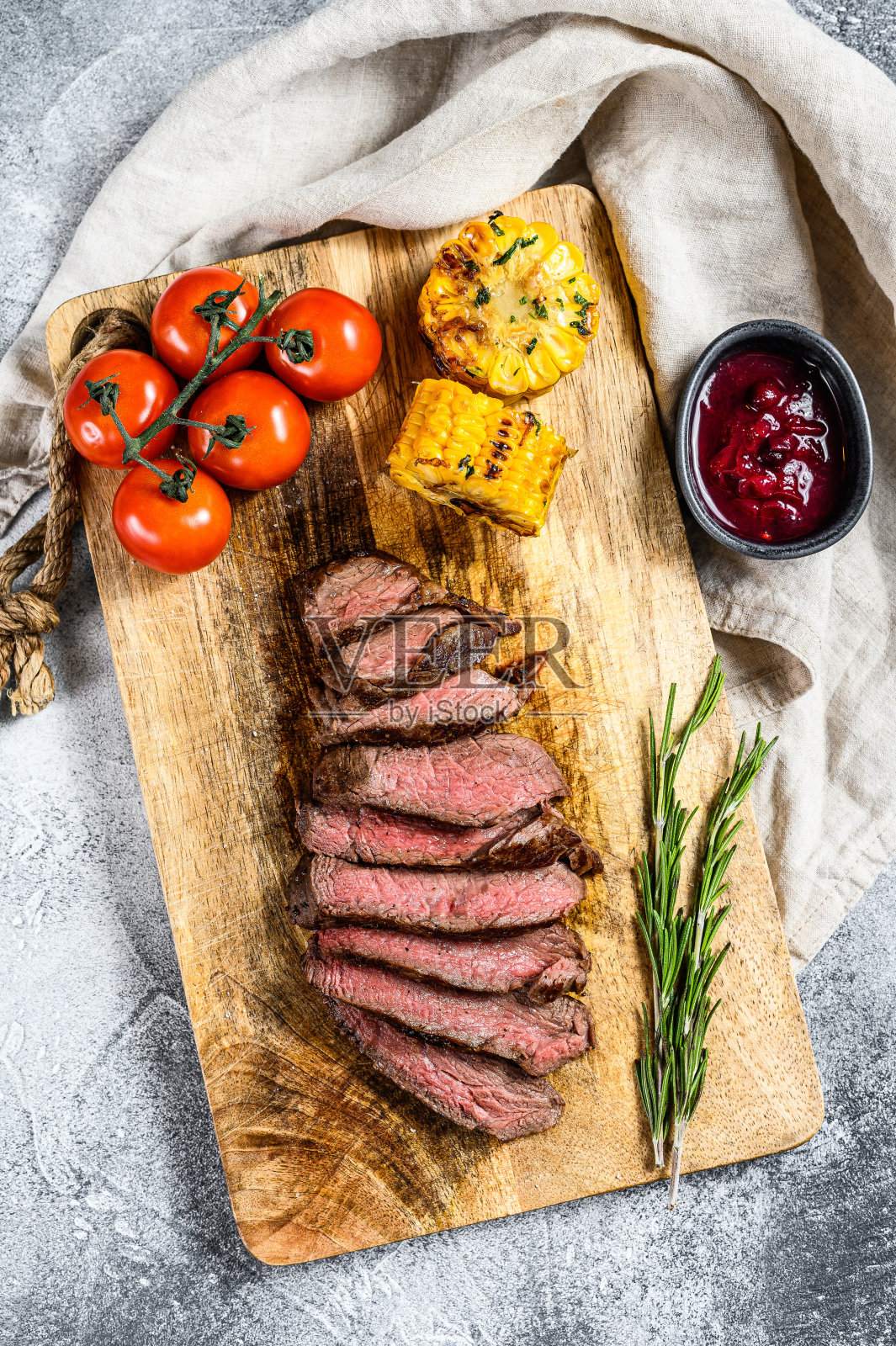 切好的烤菲力牛排放在木砧板上。牛肉里脊。灰色的背景。俯视图照片摄影图片