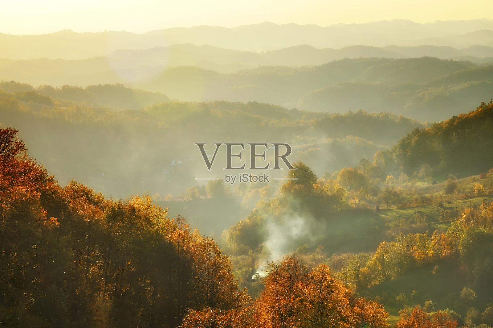 秋天的山在夕阳的薄雾中。镜头光晕效果。照片摄影图片