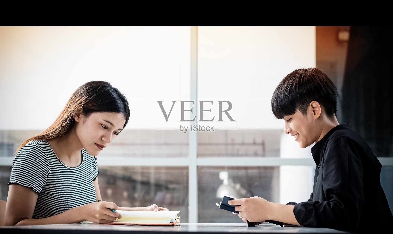 两个年轻人在会议室里一起读书、工作，周围光线模糊照片摄影图片