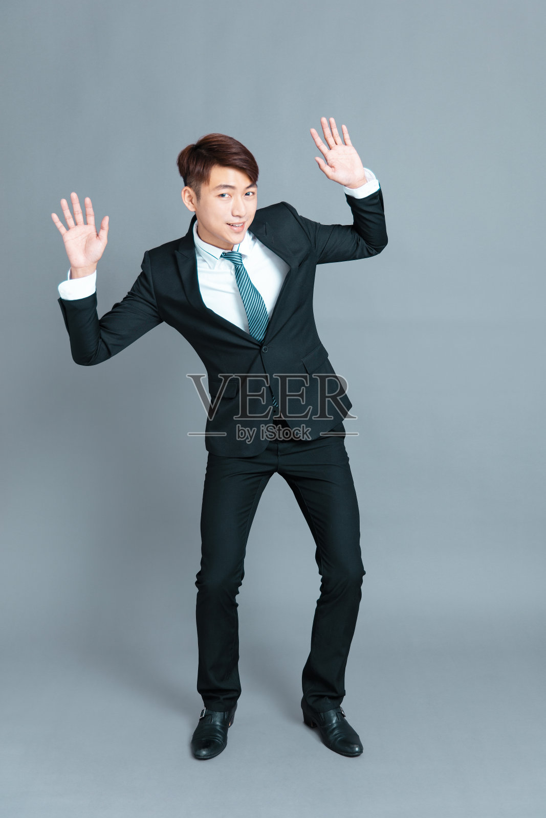 一个害怕的年轻商人站在灰色的背景前照片摄影图片