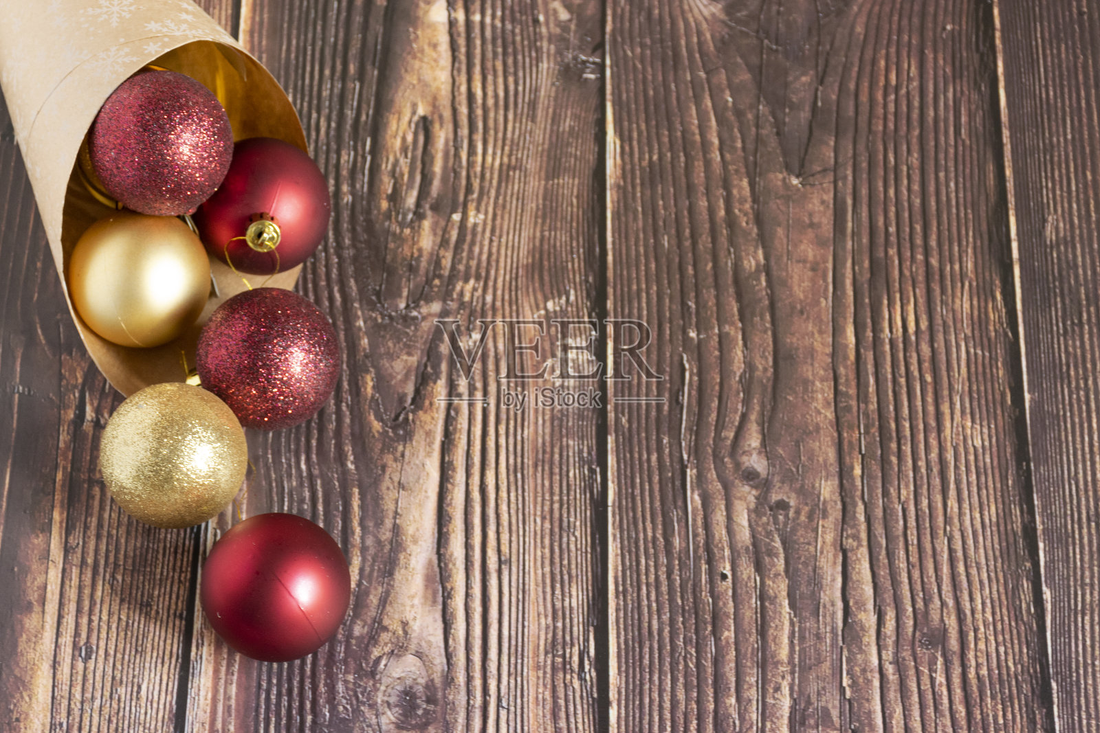 圣诞礼物，金色的，银色的，红色的圣诞球从一个用牛皮纸包裹的木制背景中喷涌而出。圣诞球。Copyspace“n照片摄影图片