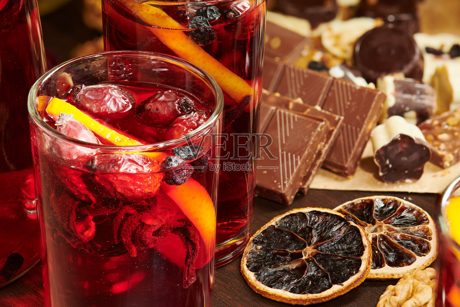 圣诞热葡萄酒或酒与香料，巧克力糖果，糖果和桔子片在乡村的桌子上，传统的冬季饮料，圣诞灯和装饰照片摄影图片