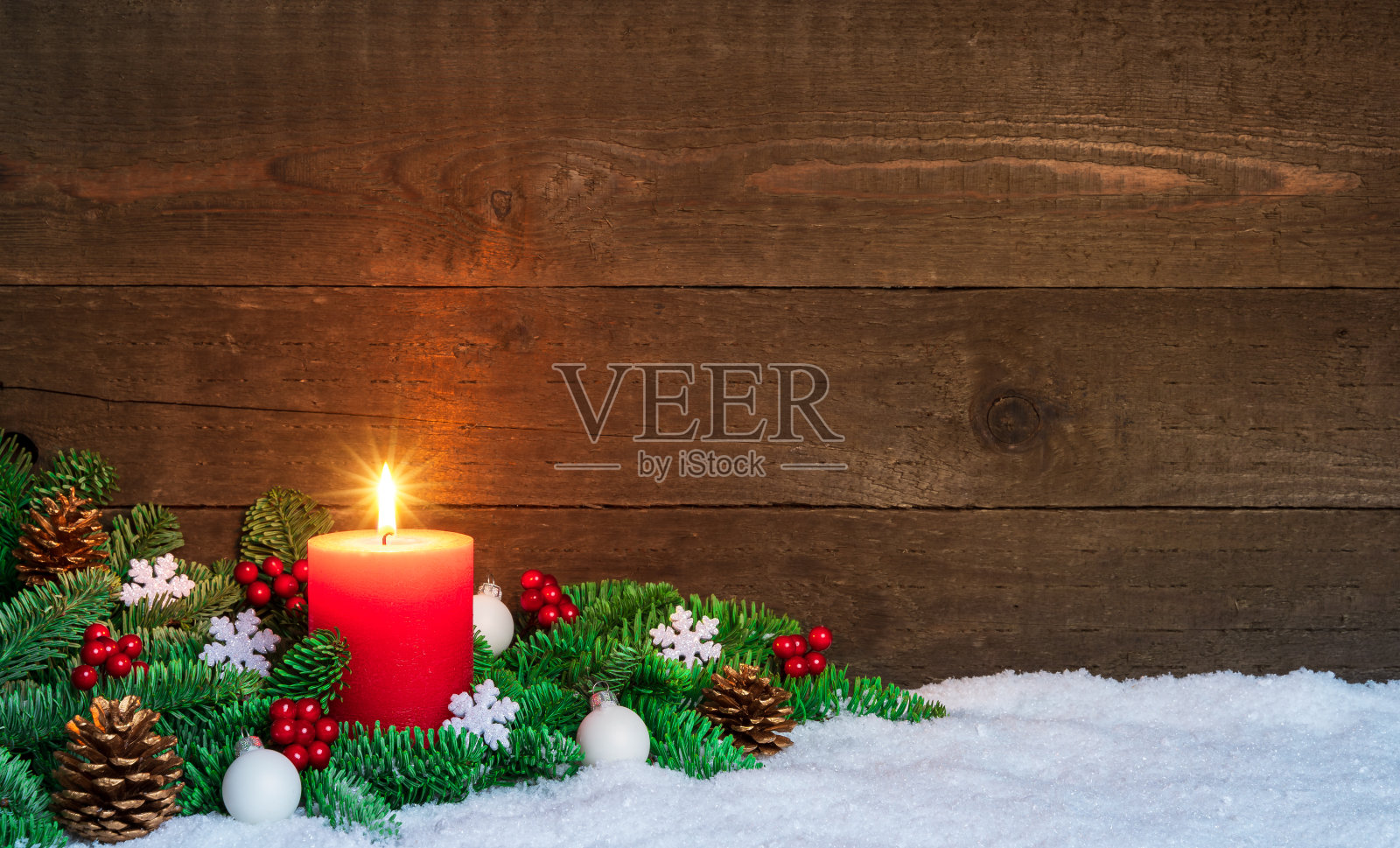 圣诞节或降临节木材的背景用燃烧的红烛在雪地上，用杉木树枝和装饰品装饰。本空间照片摄影图片