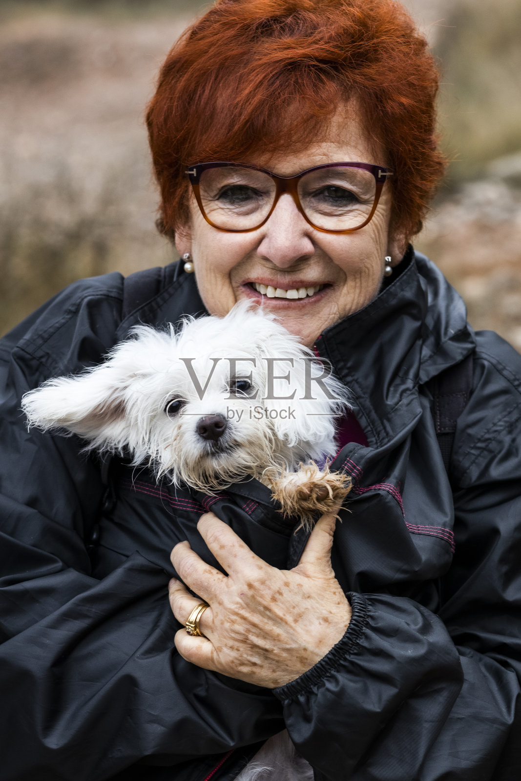 老年妇女保护一只又脏又湿的小狗免受寒冷照片摄影图片