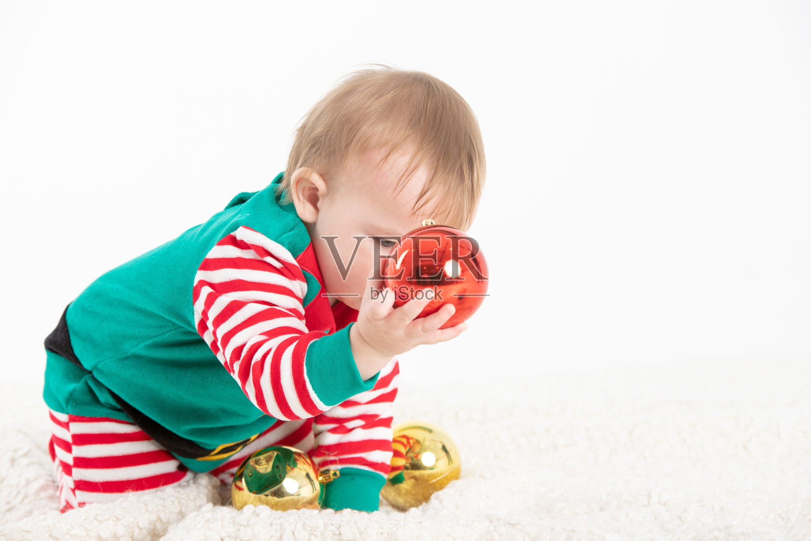 穿着精灵服装的婴儿抓住圣诞球照片摄影图片