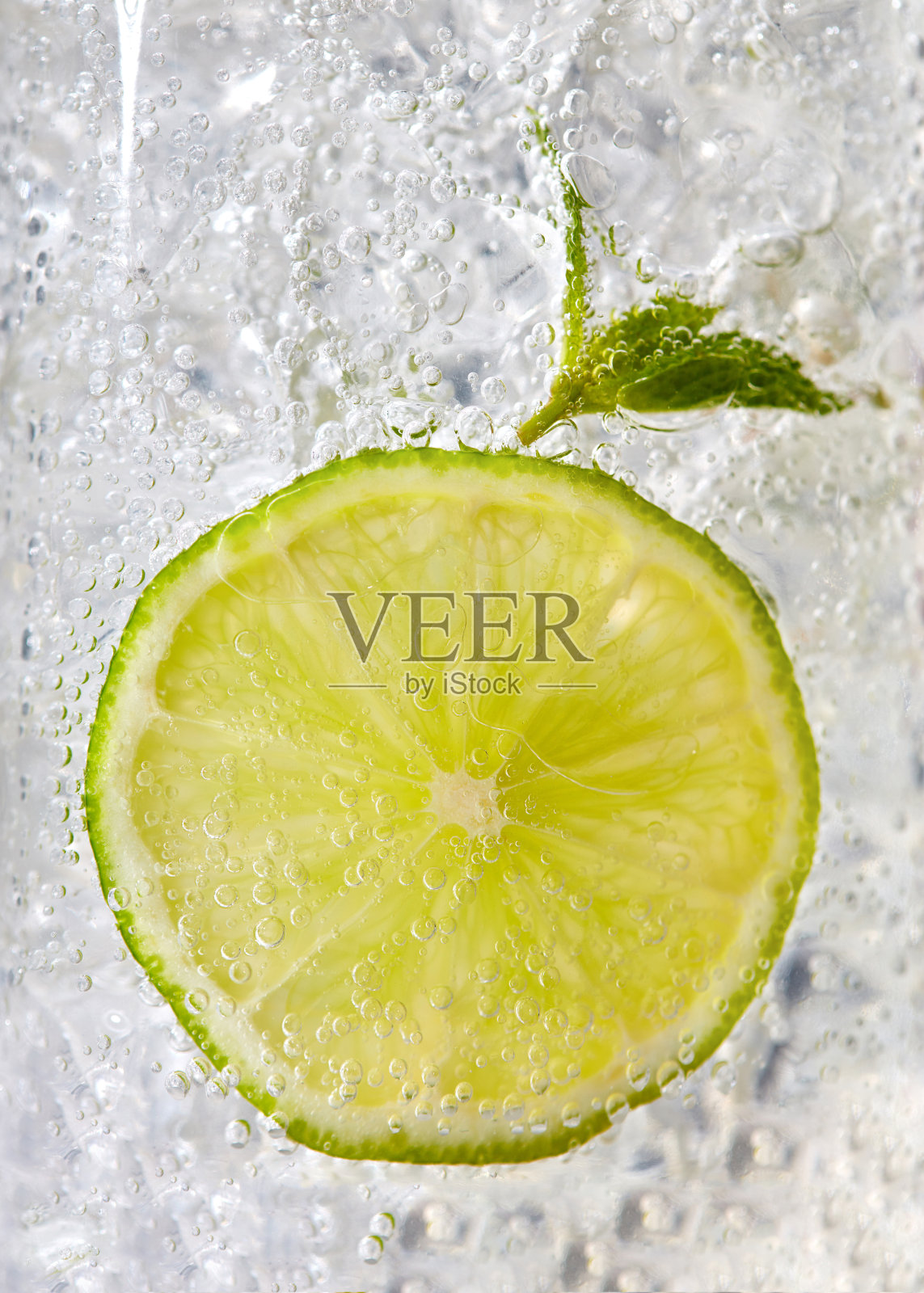 微距照片一片酸橙和薄荷叶在一个玻璃与冰和泡沫。冷夏饮品概念照片摄影图片