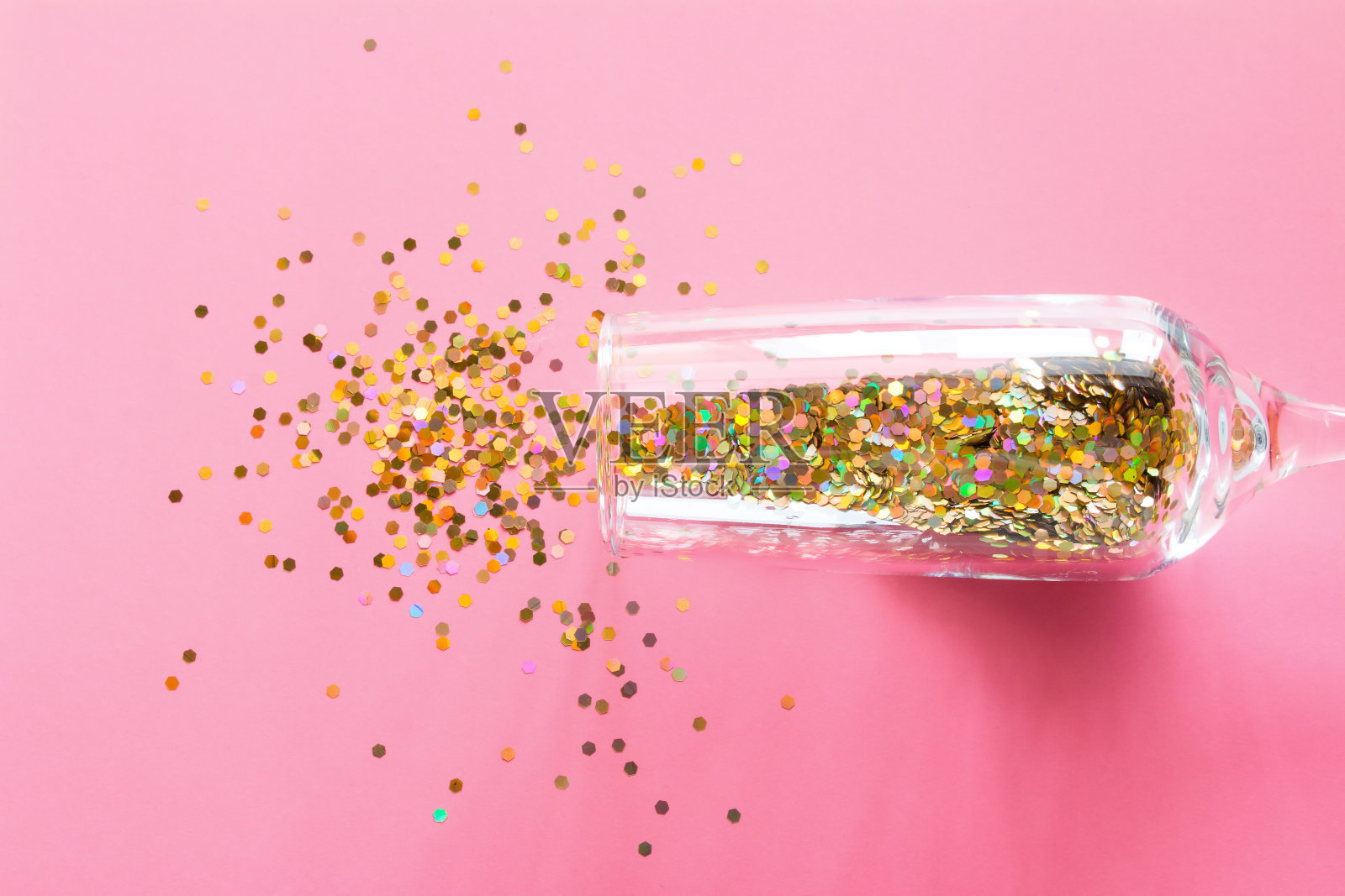一杯香槟，撒上五彩纸屑。粉色背景下的圣诞爆竹概念照片摄影图片