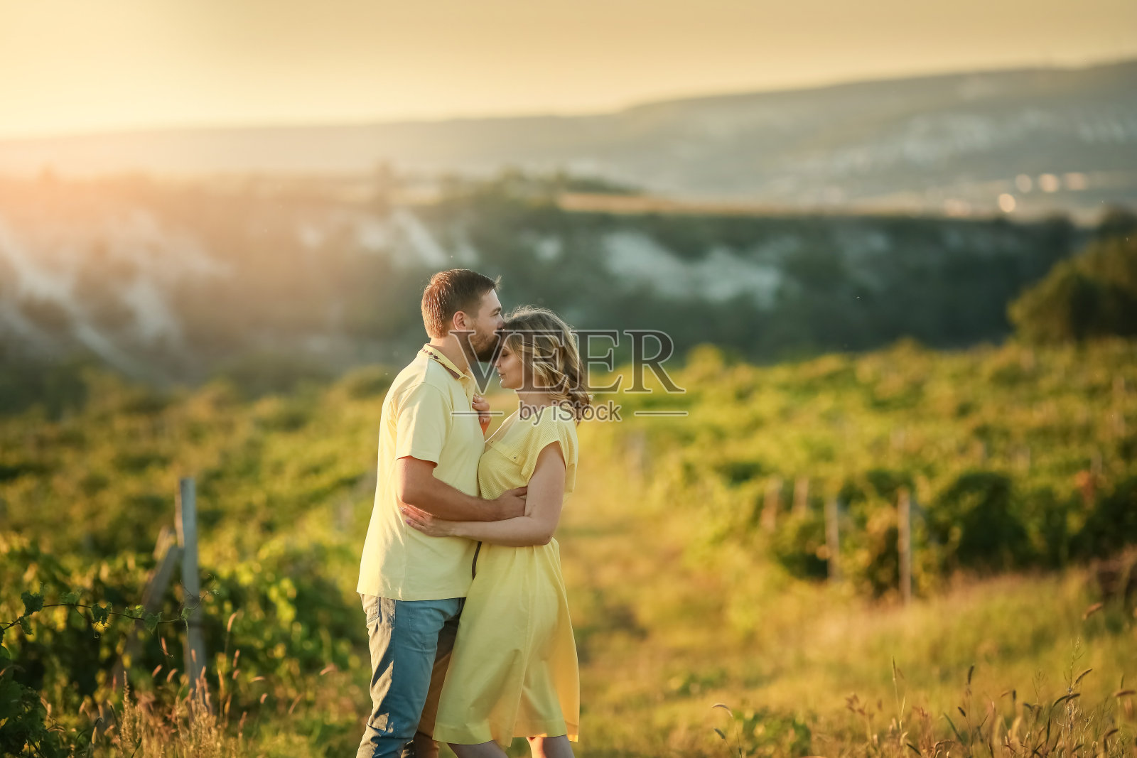 年轻的家庭和女儿走在草地在山的背景照片摄影图片