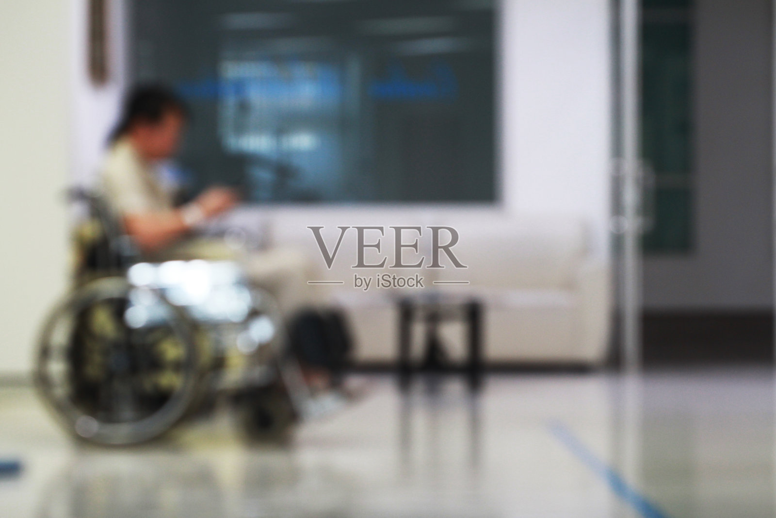 模糊的形象。背景模糊的一名男子坐在轮椅上在医院等待治疗。健康护理或家庭关系概念。照片摄影图片