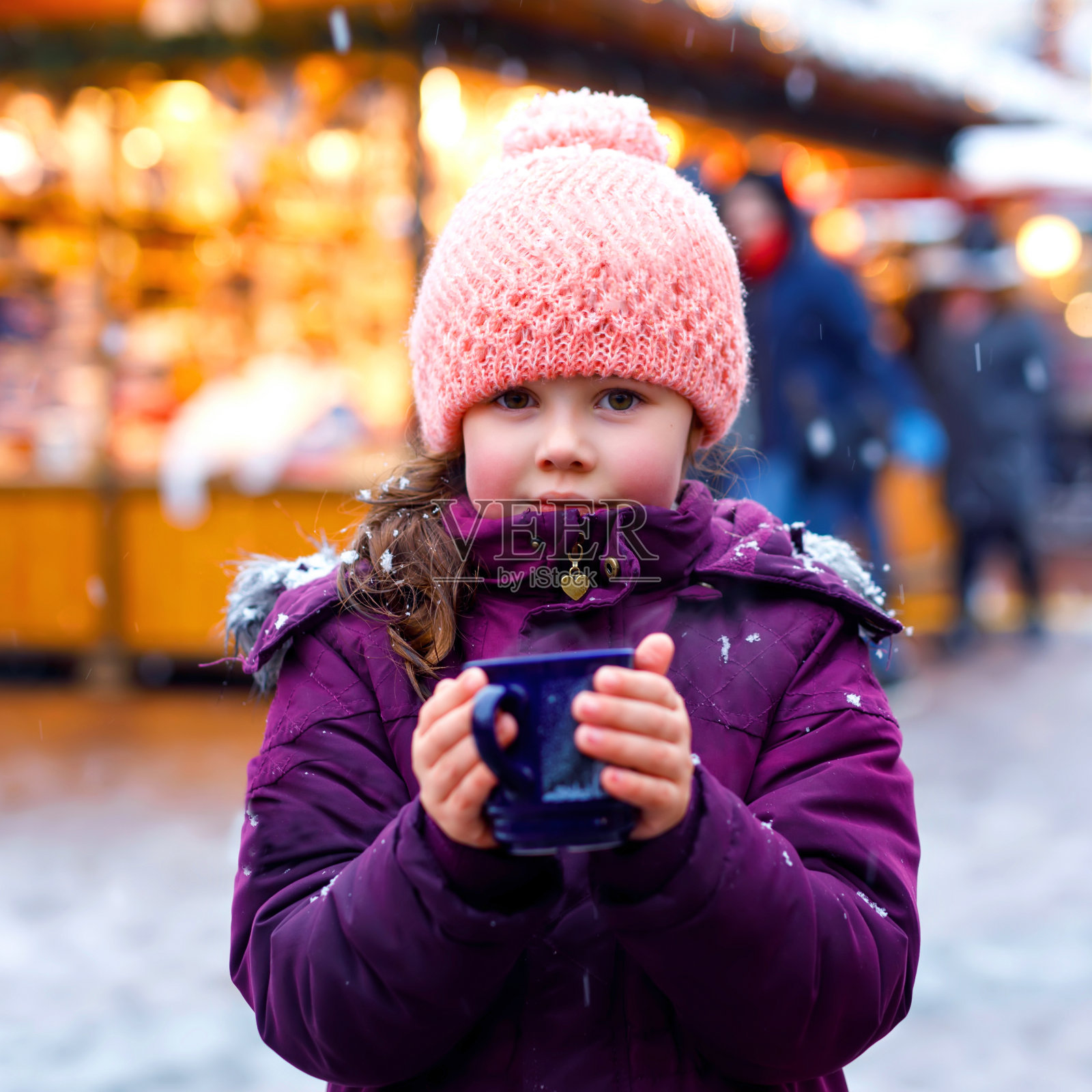 可爱的小女孩与一杯热气腾腾的巧克力或儿童潘趣酒。德国圣诞市场上快乐的孩子。传统休闲家庭在圣诞节。照片摄影图片
