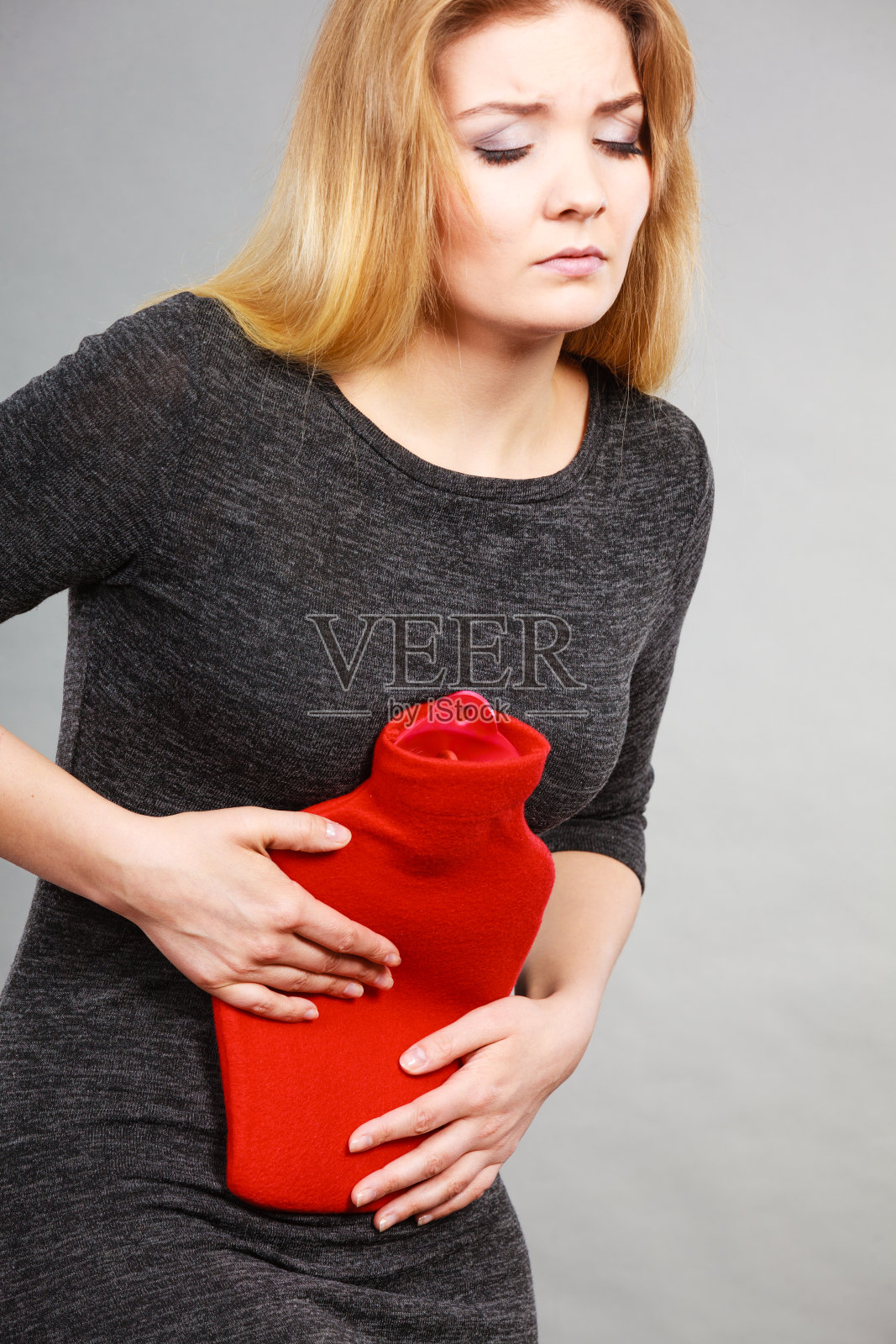 女孩胃疼，拿着热水瓶照片摄影图片