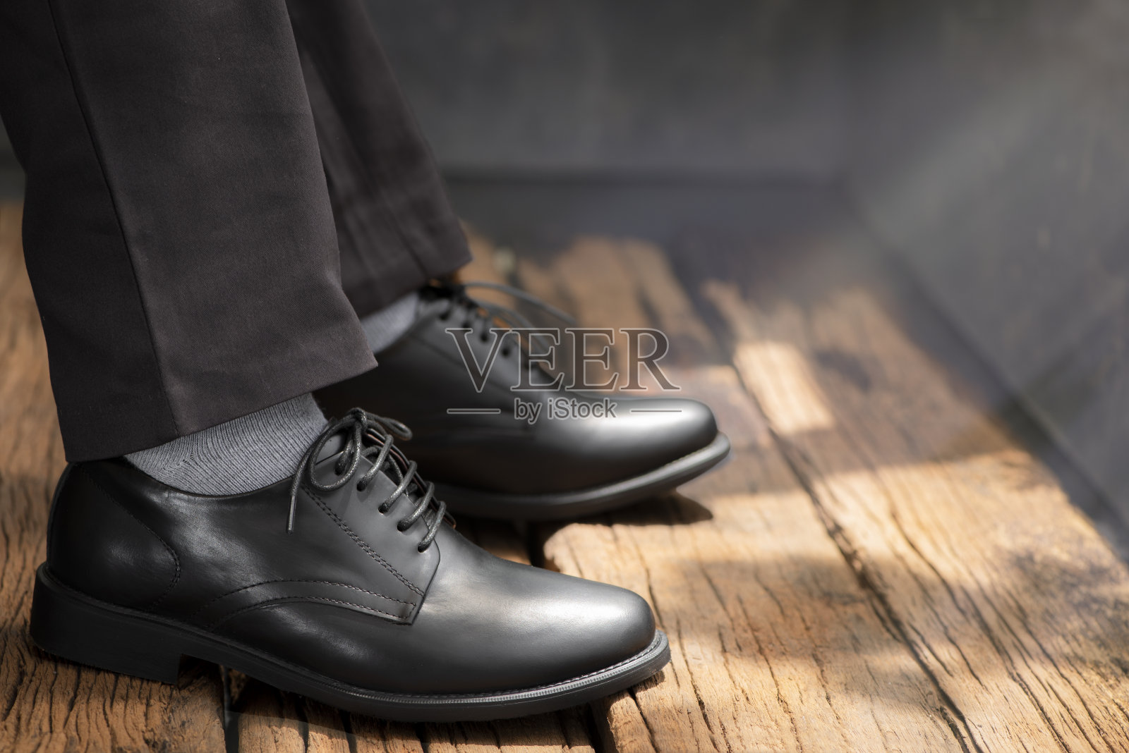 男模特穿着长裤和黑皮鞋在木地板上。照片摄影图片