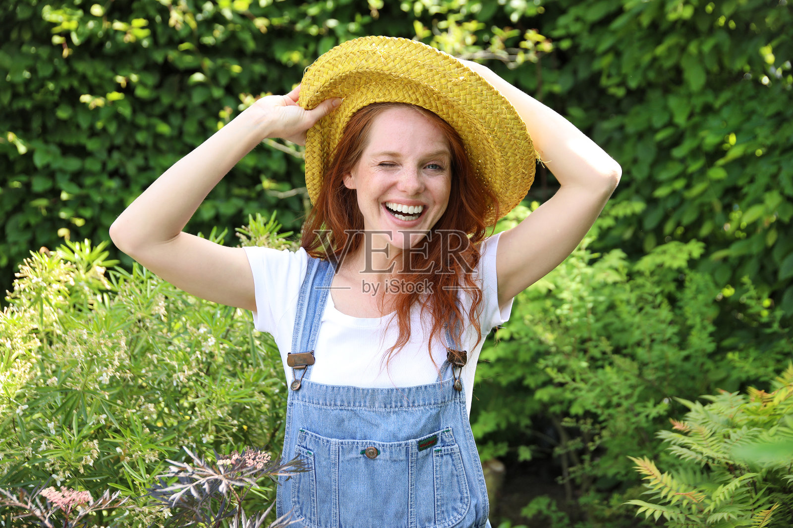 漂亮的女人红头发和黄色太阳帽在花园里工作照片摄影图片