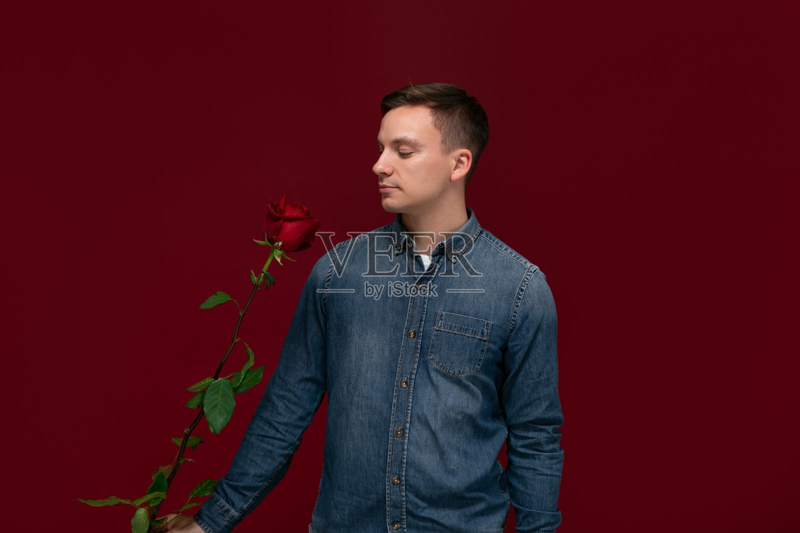 年轻漂亮的男人手持红玫瑰送给爱人，充满浪漫气息照片摄影图片