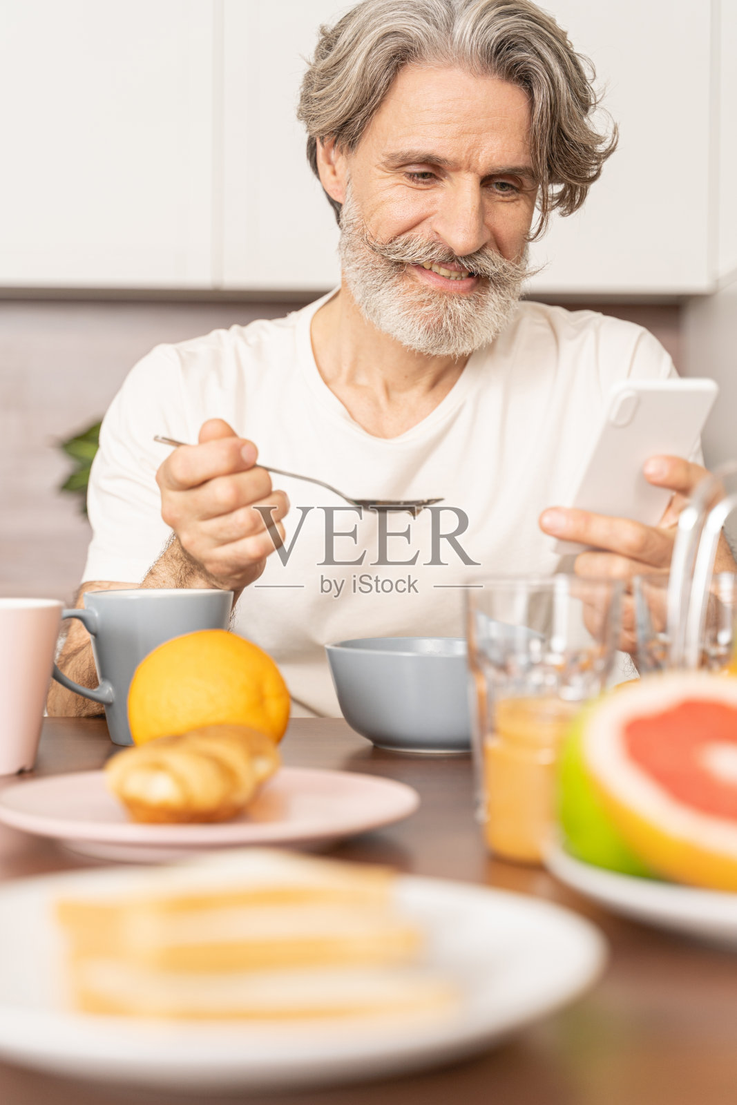 中年男子拿着手机吃早餐照片摄影图片
