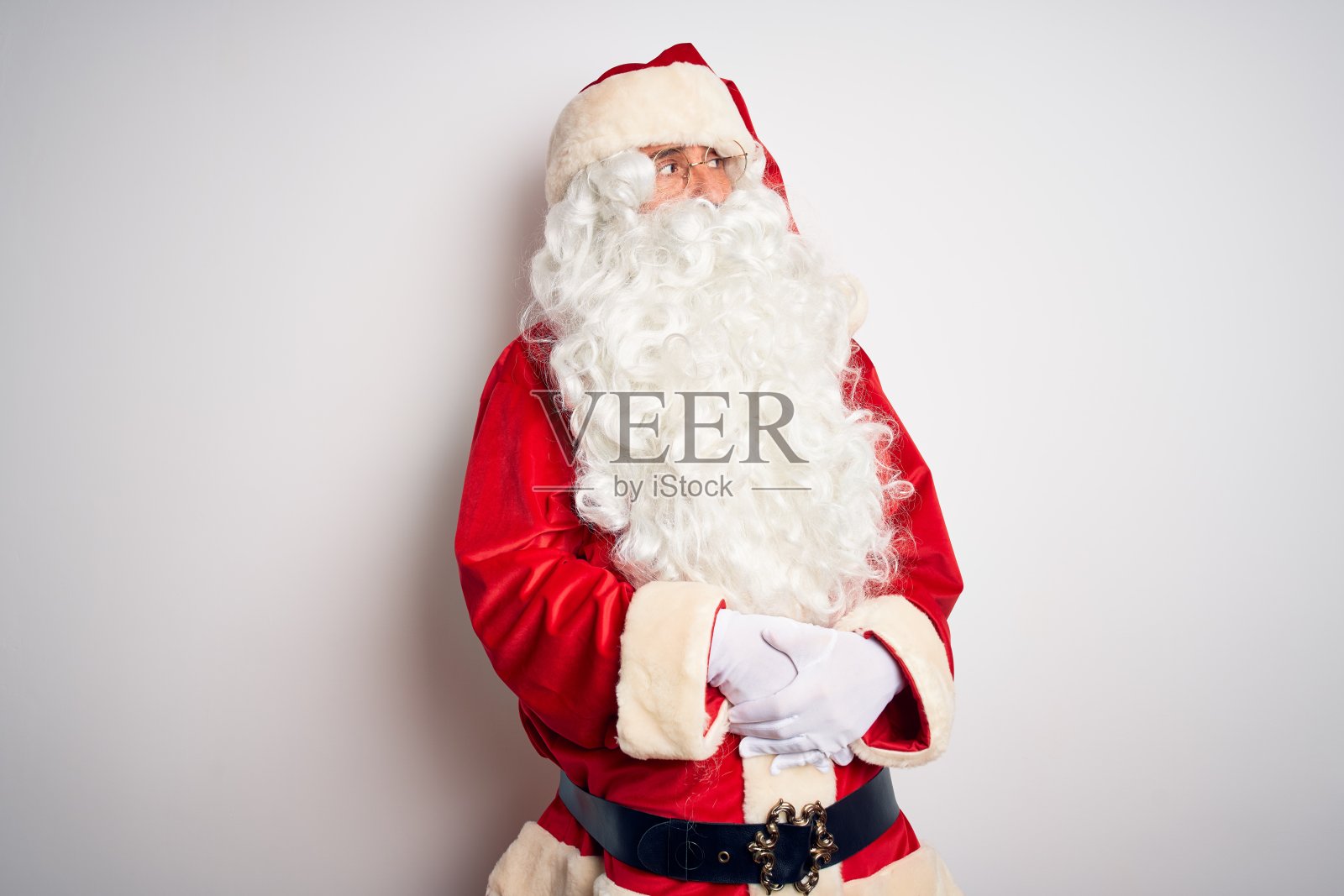 中年英俊的男人穿着圣诞老人服装站在孤立的白色背景看一边与双臂交叉确信和自信照片摄影图片