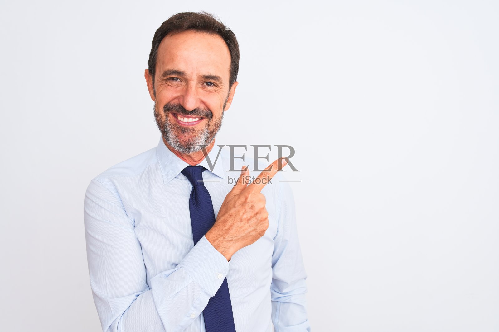 中年商人戴着优雅的领带，站在孤立的白色背景愉快地微笑着指着与手和手指向上的一边，脸上的快乐和自然的表情照片摄影图片