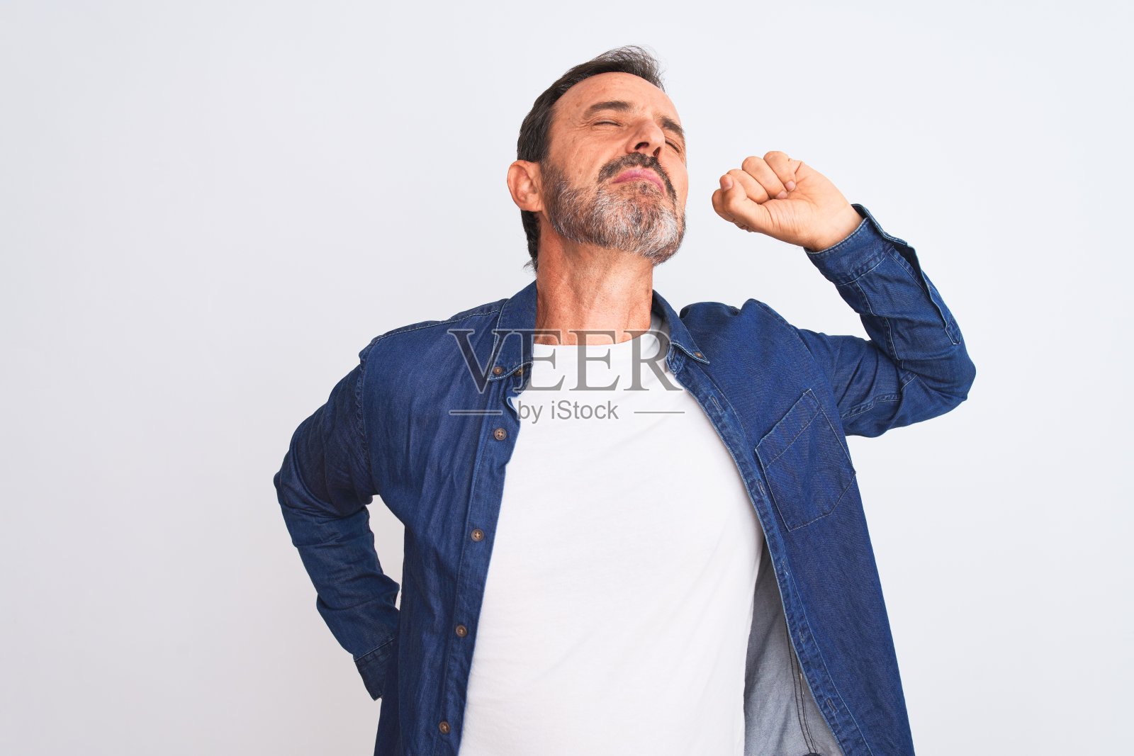 中年英俊男子穿着蓝色牛仔衬衫站在孤立的白色背景伸展，疲倦和放松，困倦和打哈欠的清晨照片摄影图片