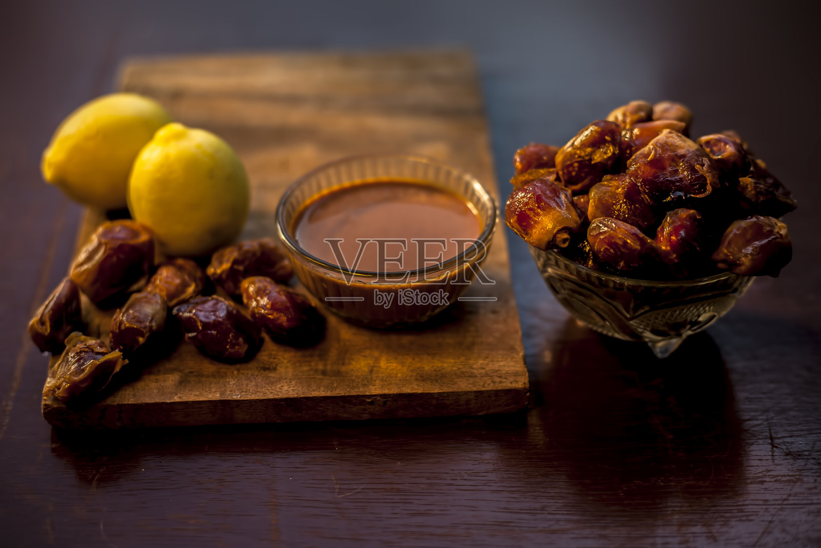 红枣果面膜在一个由一些红枣和柠檬汁组成的玻璃碗，适合油性皮肤。适用于油性或脂溢性皮肤的枣子面膜的水平井创意灯光效果。照片摄影图片