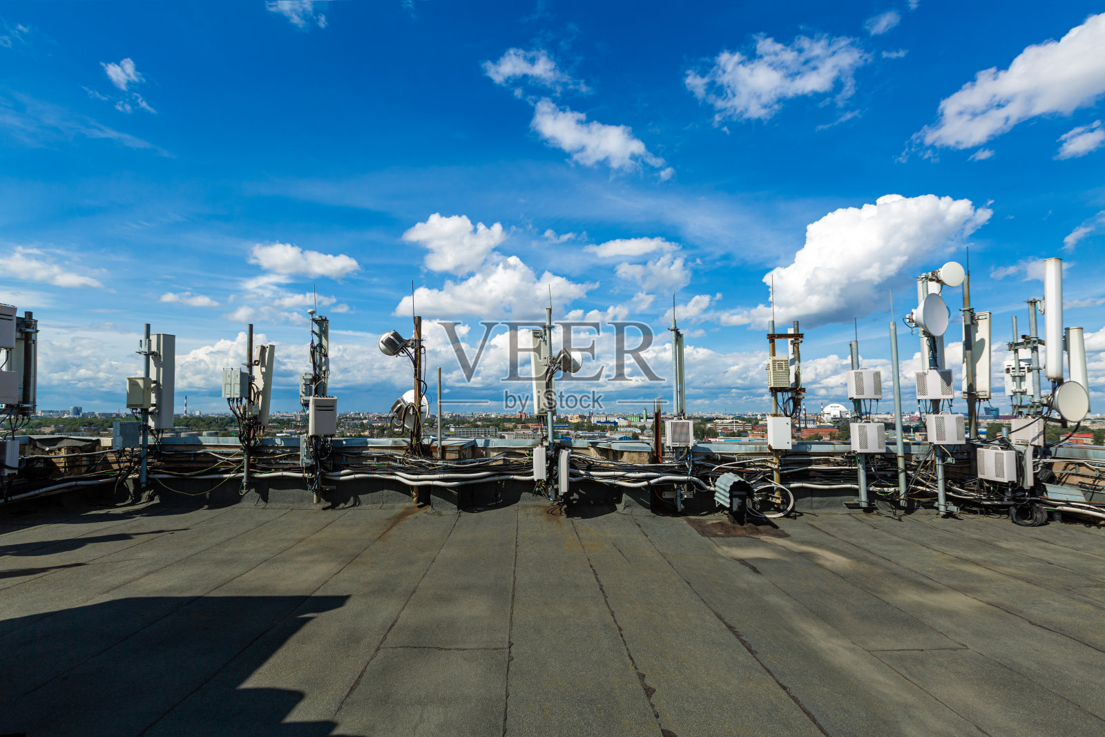 通信数据设备、无线电面板天线、室外遥控无线电设备、电力电缆、同轴电缆、光纤等安装在城市建筑的屋顶上照片摄影图片