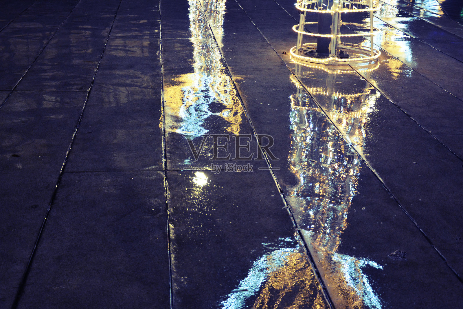 圣诞彩灯映在街上，下雨天。照片摄影图片