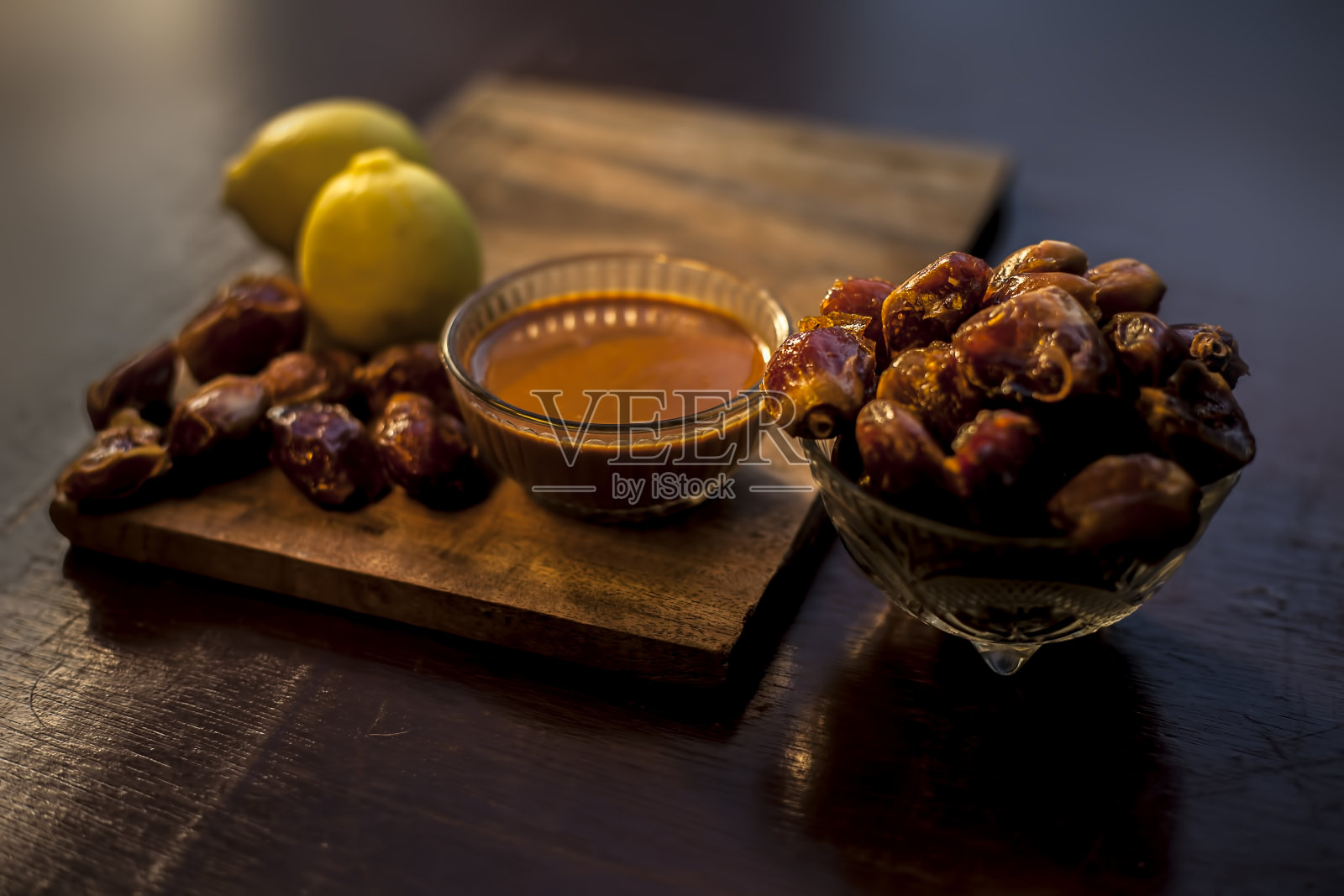 红枣果面膜在一个由一些红枣和柠檬汁组成的玻璃碗，适合油性皮肤。适用于油性或脂溢性皮肤的枣子面膜的水平井创意灯光效果。照片摄影图片