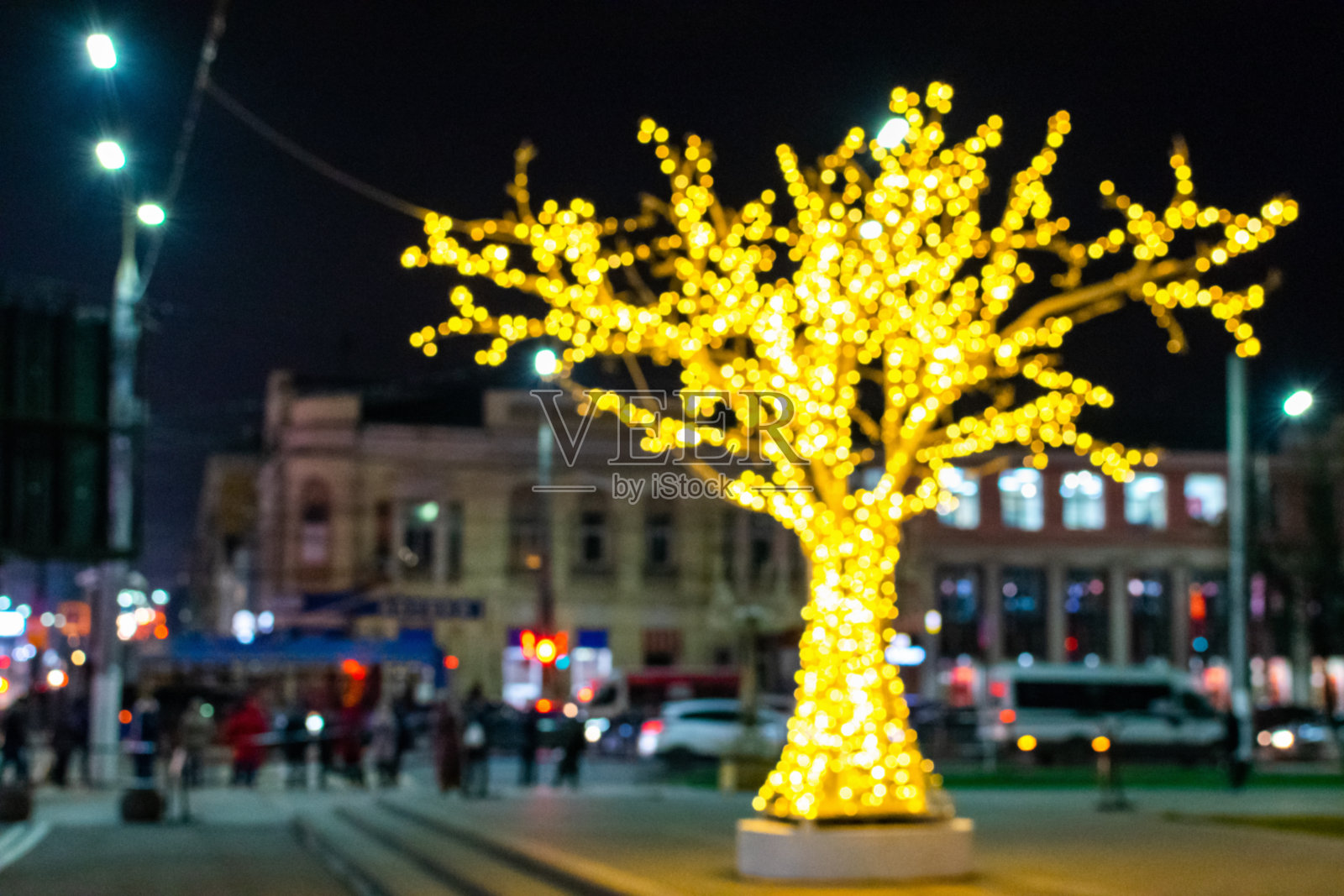 圣诞灯饰的形式在城市广场上闪闪发光的金色花环的圣诞树。模糊的新年背景与复制空间。照片摄影图片