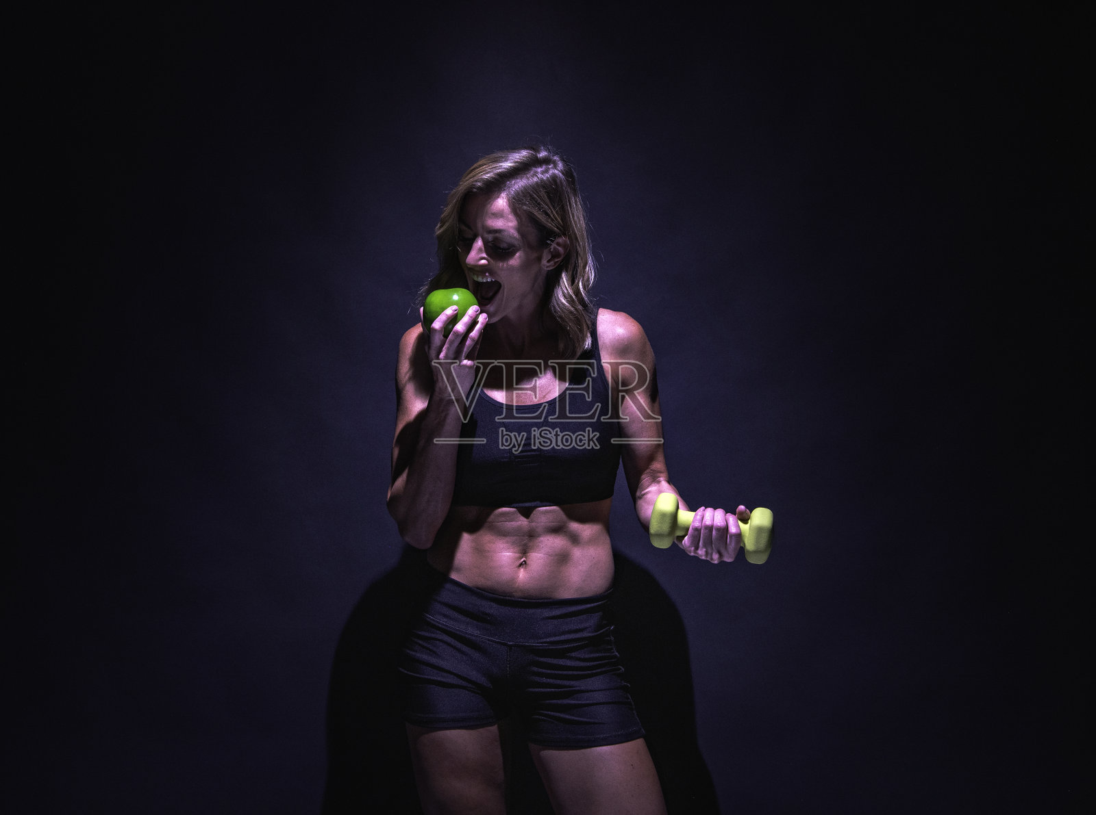 一个人/腰部以上/正面视图20-29岁的成年美丽的白人年轻女性/女性站在/锻炼前的黑色背景，穿着运动服装/运动胸罩/短裤/跑步短裤谁是微笑/快乐/愉快照片摄影图片