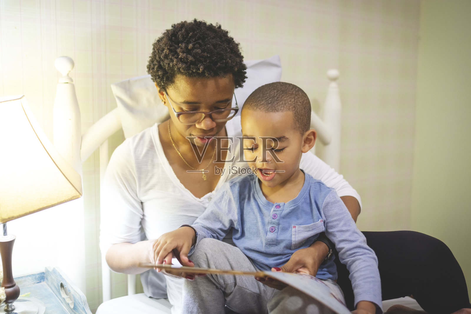 妈妈躺在床上给儿子读故事照片摄影图片