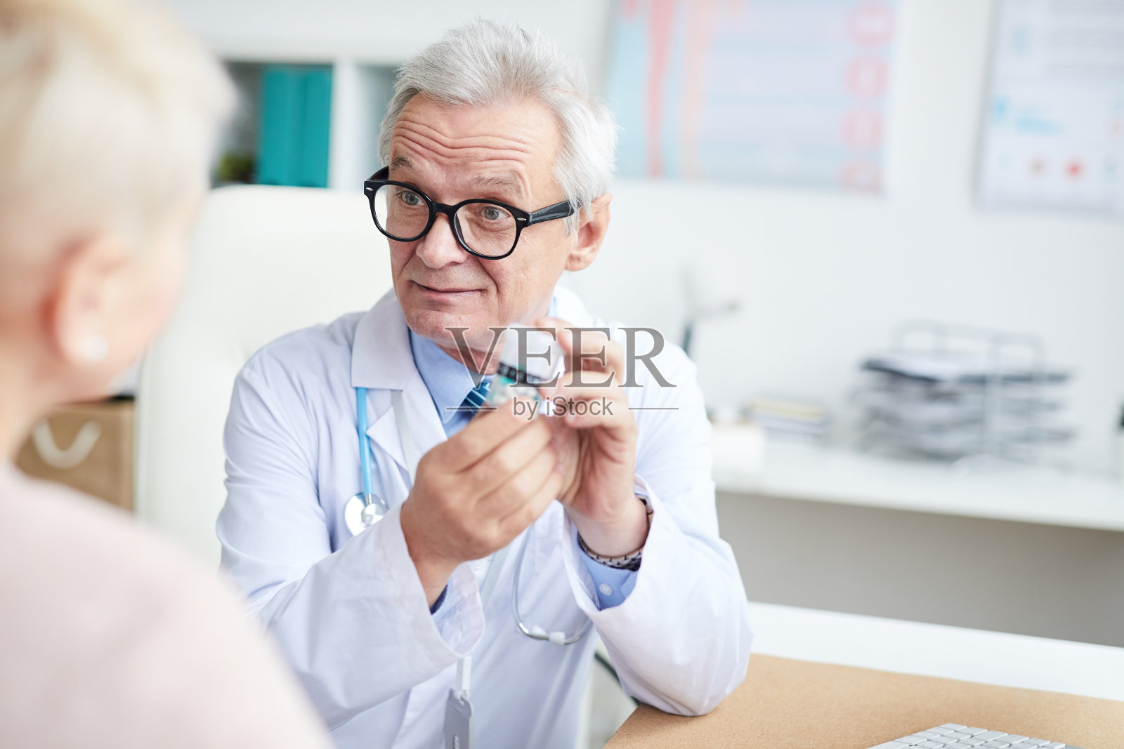 内容高级医师在眼镜皱眉前额，而处方药丸的病人在咨询照片摄影图片