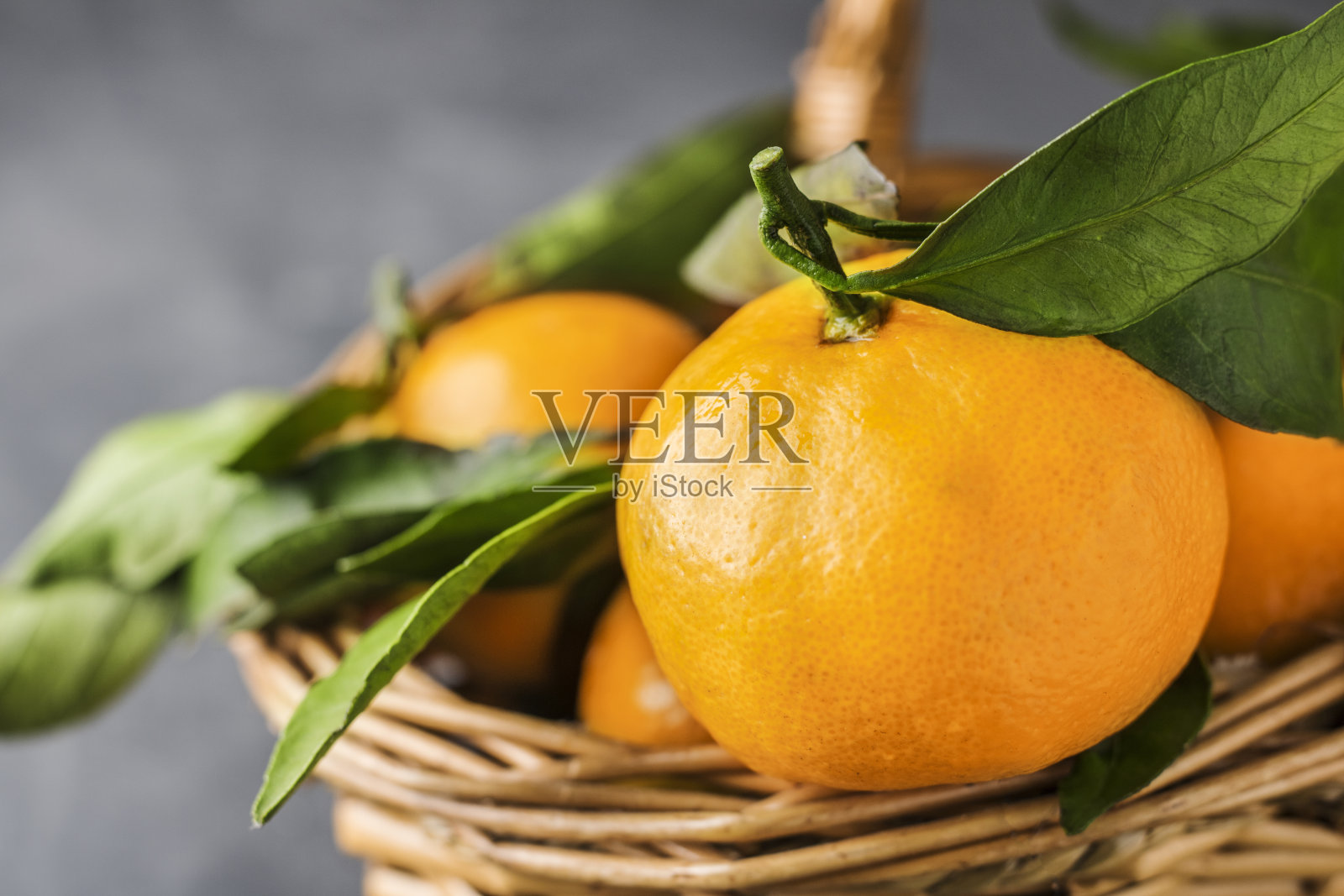 蓝灰色背景下的绿叶柑橘篮子。本空间照片摄影图片