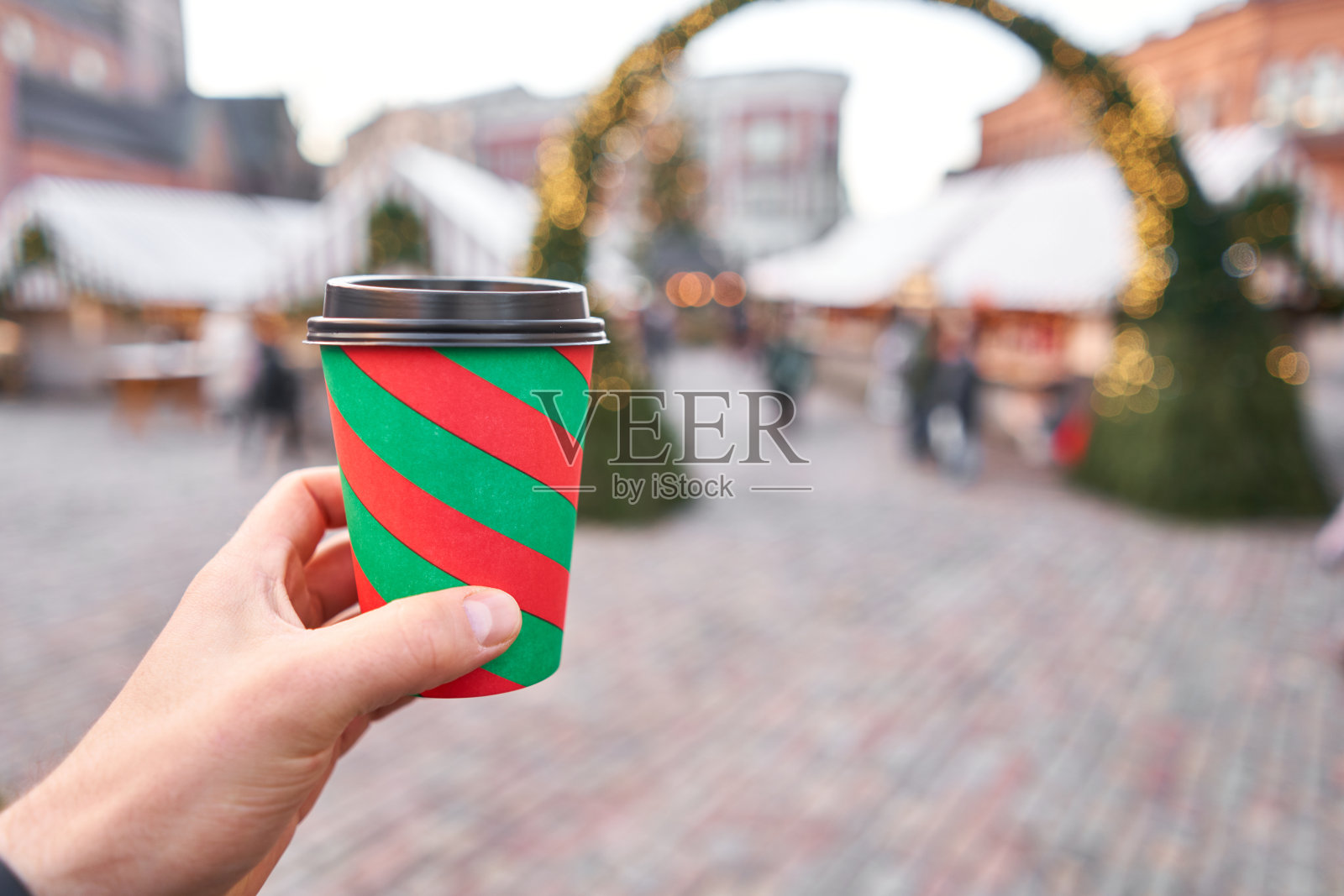 手捧一杯热红酒，背景模糊的冬季仙境，一个欧洲小城市的圣诞市场照片摄影图片